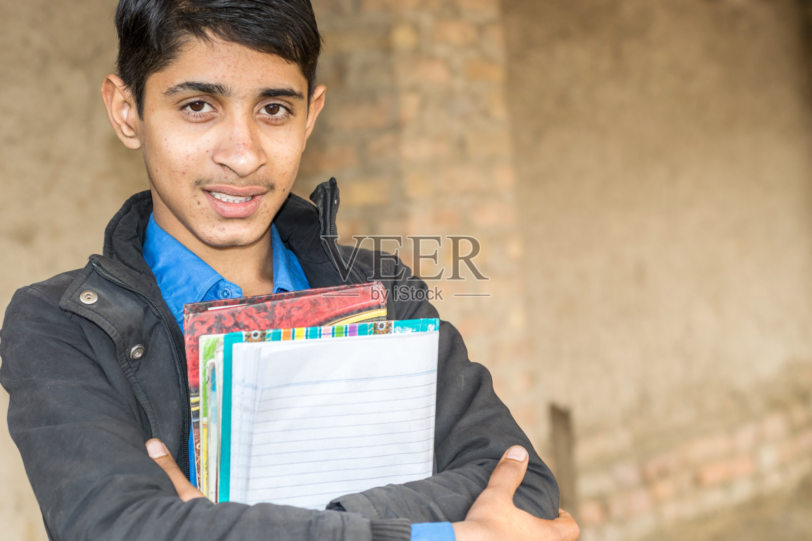 一个年轻的学生穿着校服，拿着书，感到快乐照片摄影图片