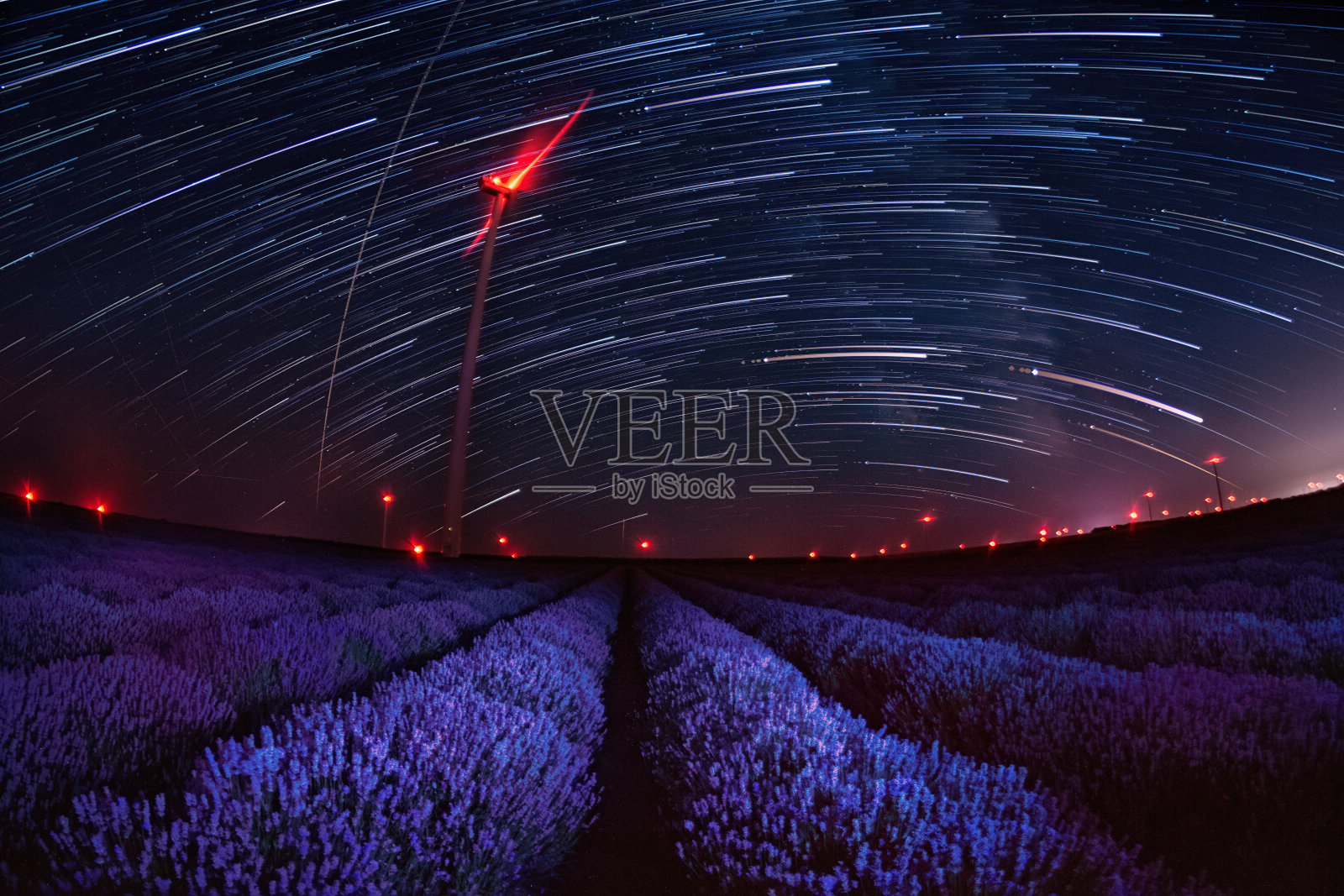 美丽的星夜景观，星星的轨迹在薰衣草和红色的风力涡轮机的灯光田野照片摄影图片
