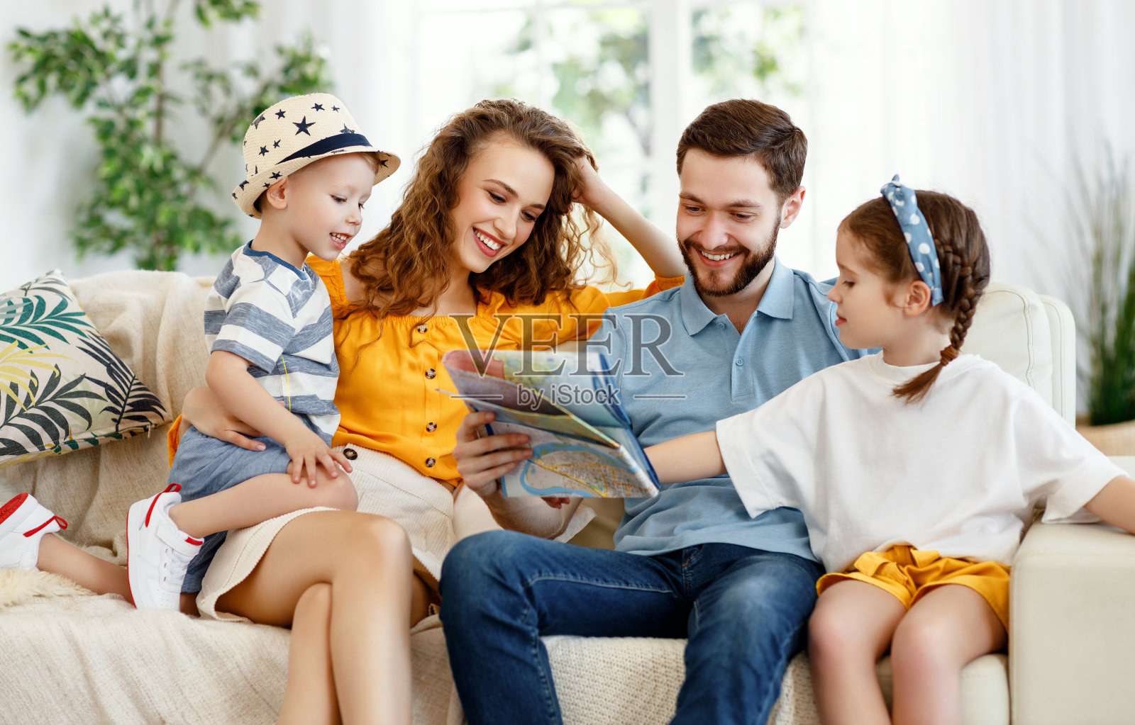 兴高采烈的父母带着孩子在家里的沙发上看地图照片摄影图片
