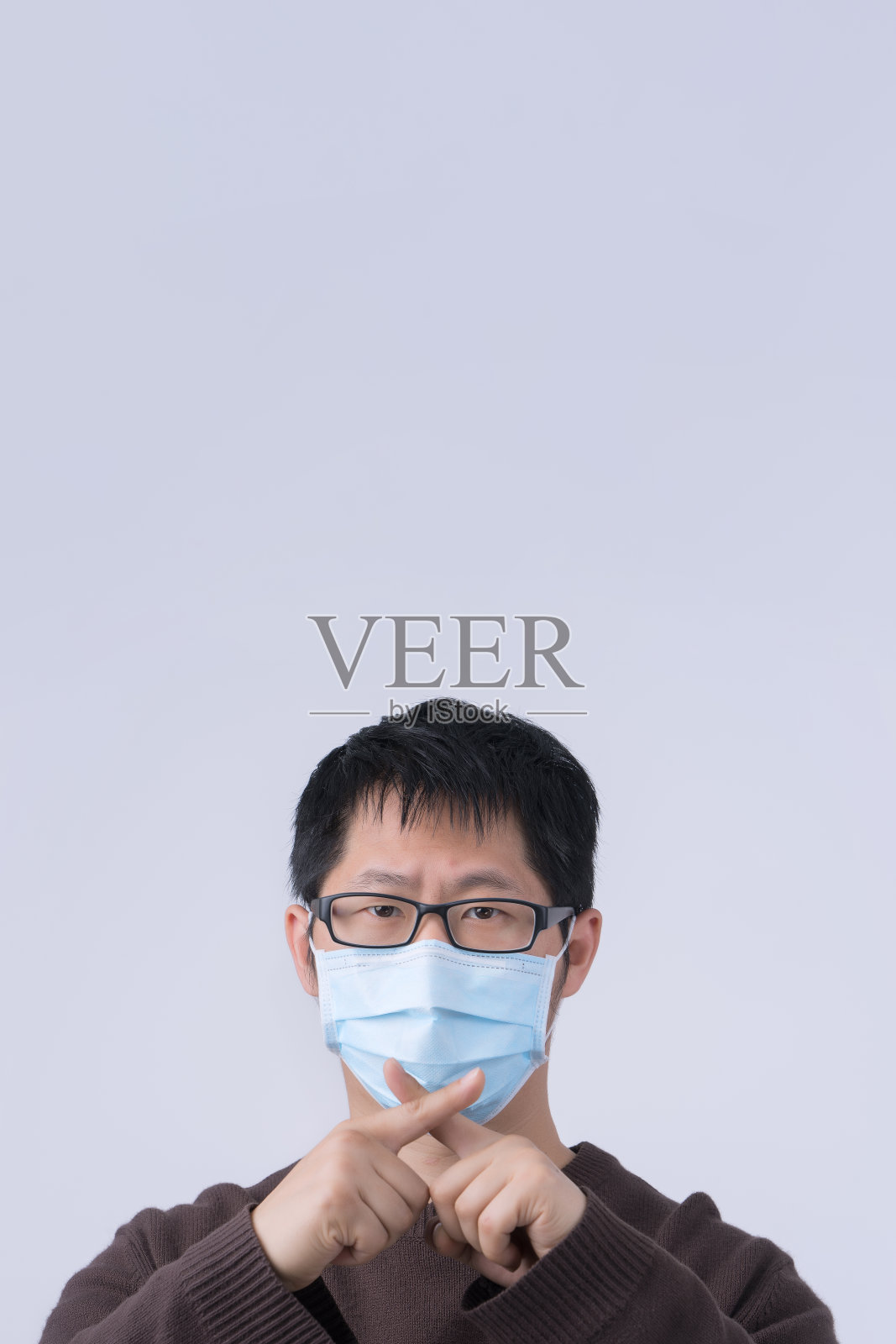 这是一幅年轻亚洲男子的肖像，他戴着医用外科蓝色口罩，在白色背景下隔离，向冠状病毒感染说不。照片摄影图片