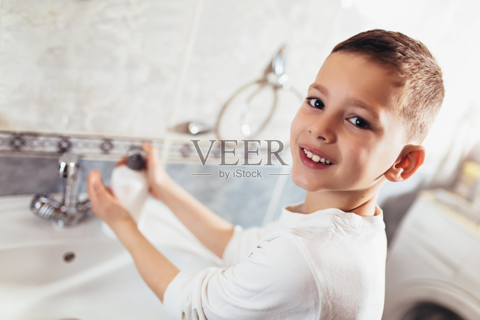 小男孩在浴室里洗手。照片摄影图片