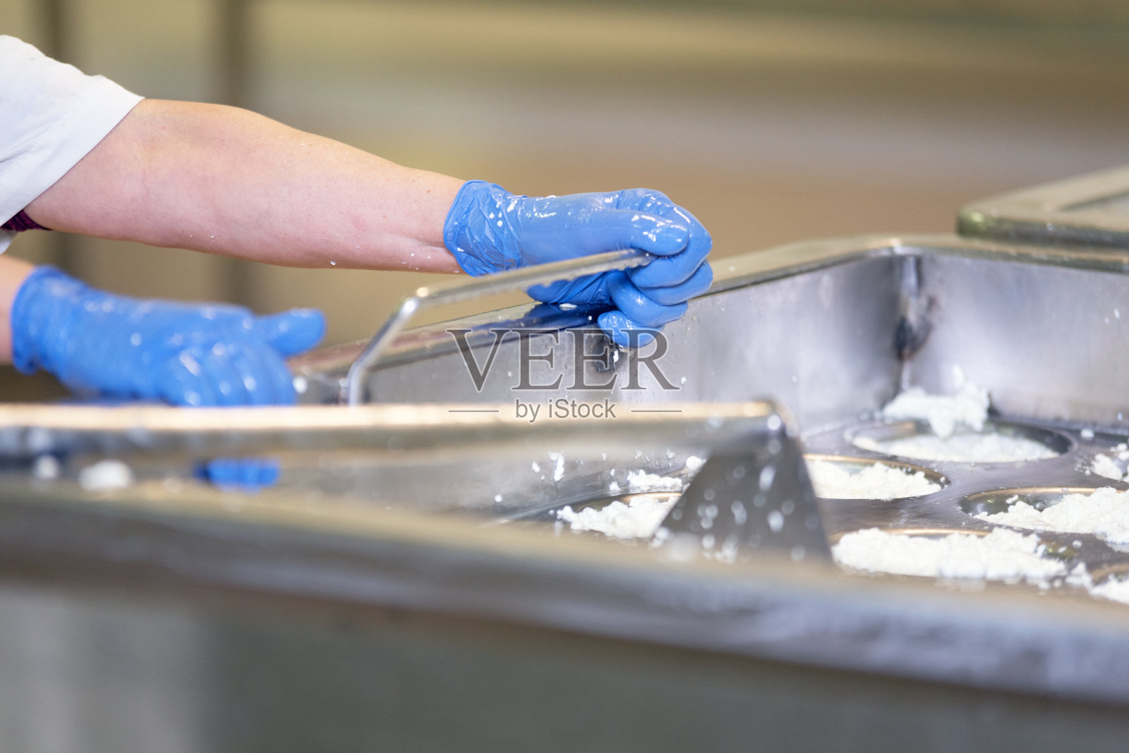 在奶酪制造厂的发酵过程中，人在不锈钢罐中搅拌牛奶。照片摄影图片