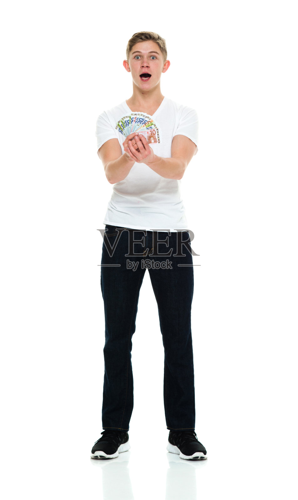 白人年轻男子穿着运动鞋，手持欧盟货币站在白色背景前照片摄影图片