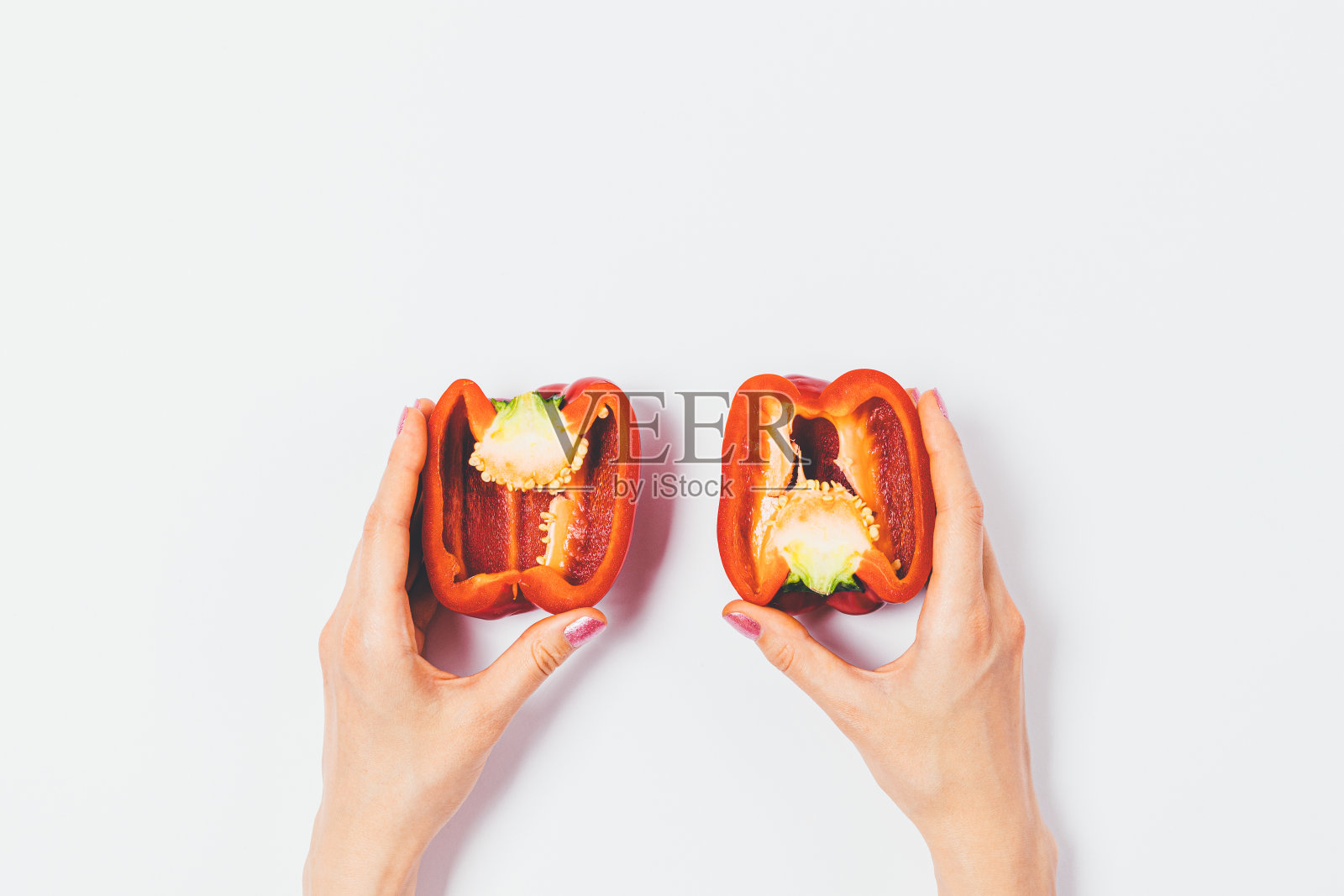 女性手里拿着切成两半的新鲜红甜椒照片摄影图片