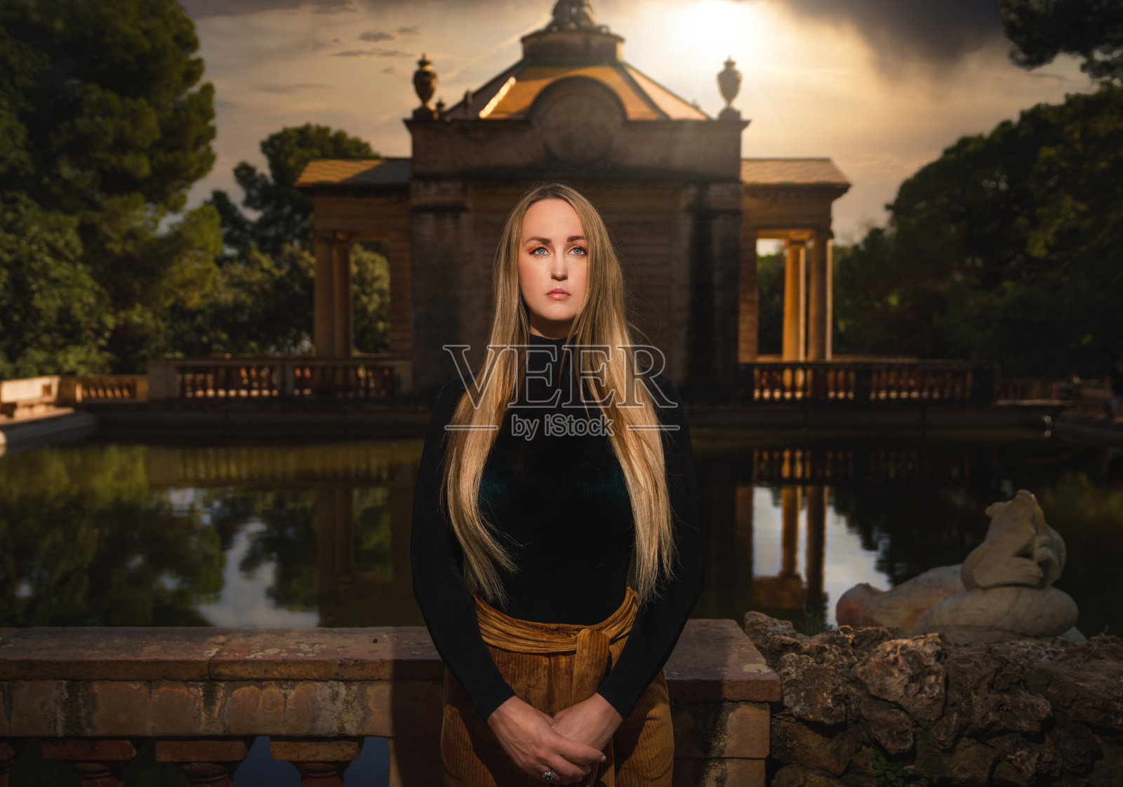 一位严肃的金发女子在西班牙的新古典主义花园前摆姿势照片摄影图片