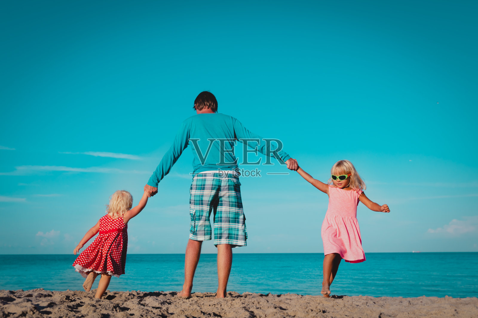 父亲和小女儿在热带海滩上玩耍照片摄影图片