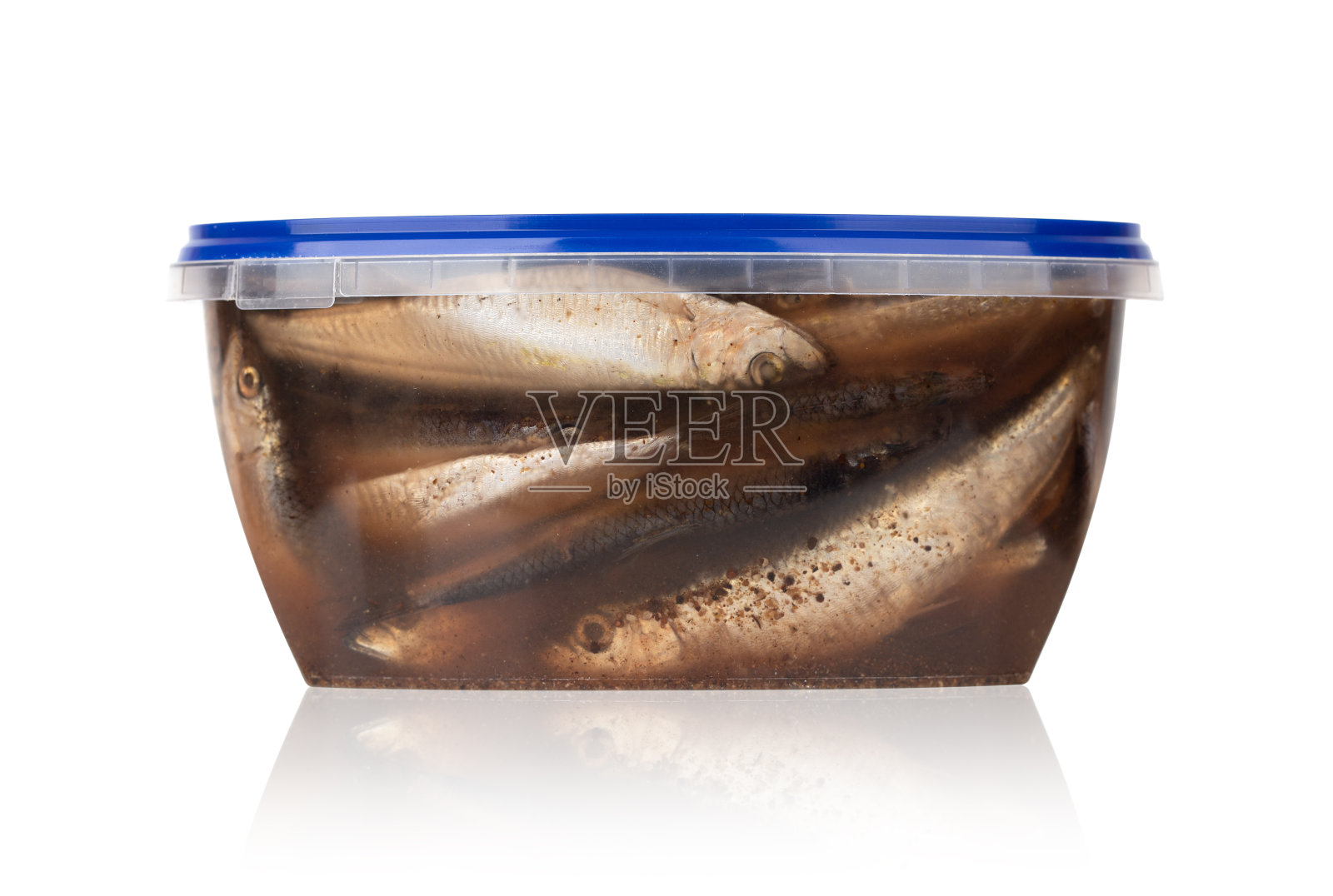 泡在罐子里的鲱鱼。白色背景的塑料容器里的腌鱼。照片摄影图片