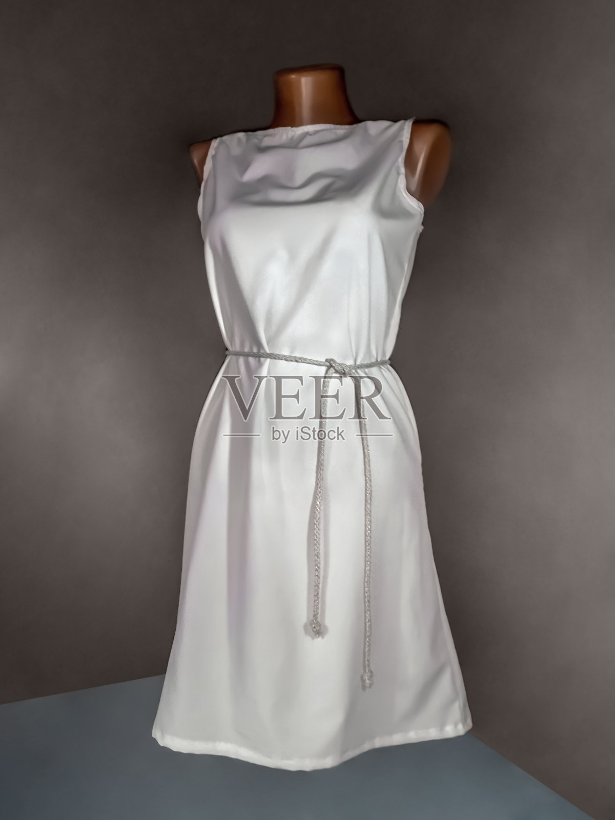 简单的白色连衣裙与皮带上的人体模型，孤立在一个黑暗的背景照片摄影图片