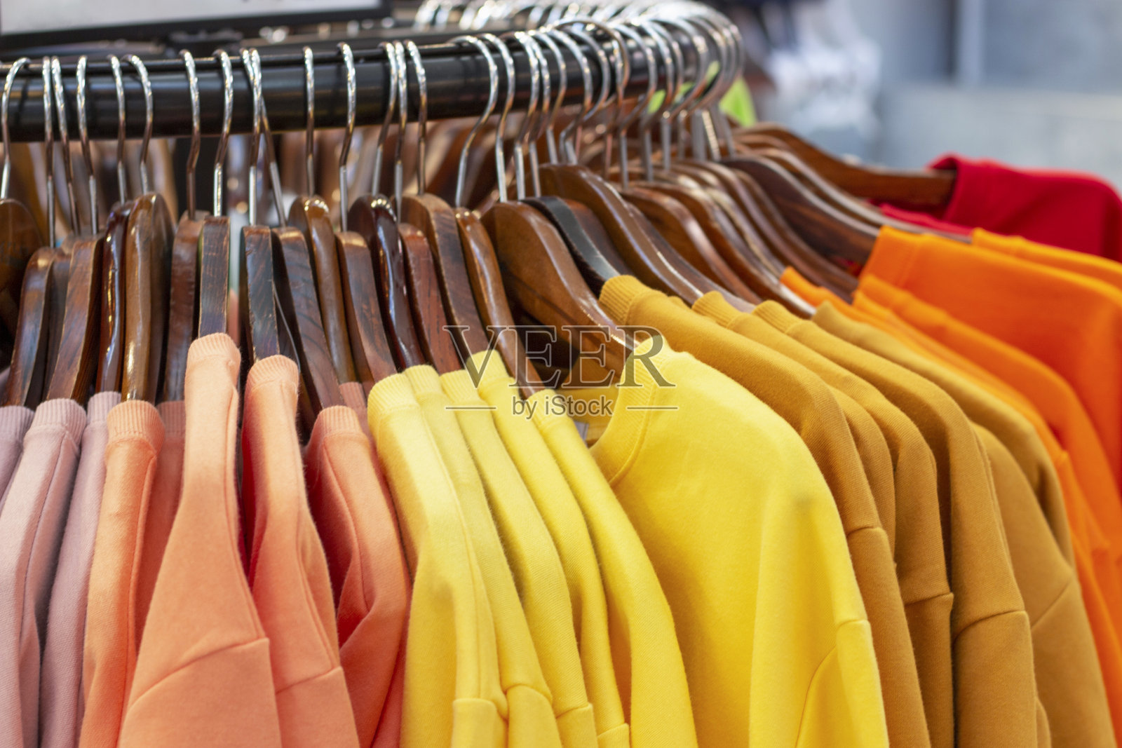 女性多色毛衣上的木制衣架在商店的特写。照片摄影图片