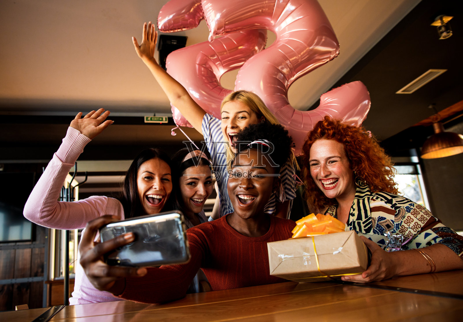 一群女孩惊喜他们的女朋友在一个咖啡店的生日聚会和自拍。照片摄影图片