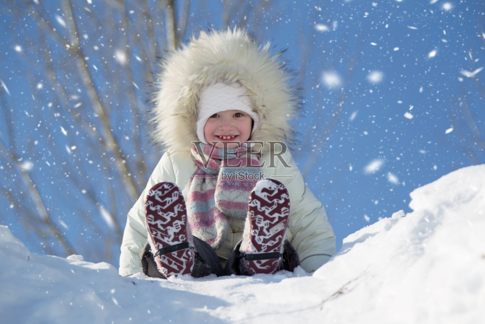 一个小女孩骑在白雪覆盖的山上照片摄影图片