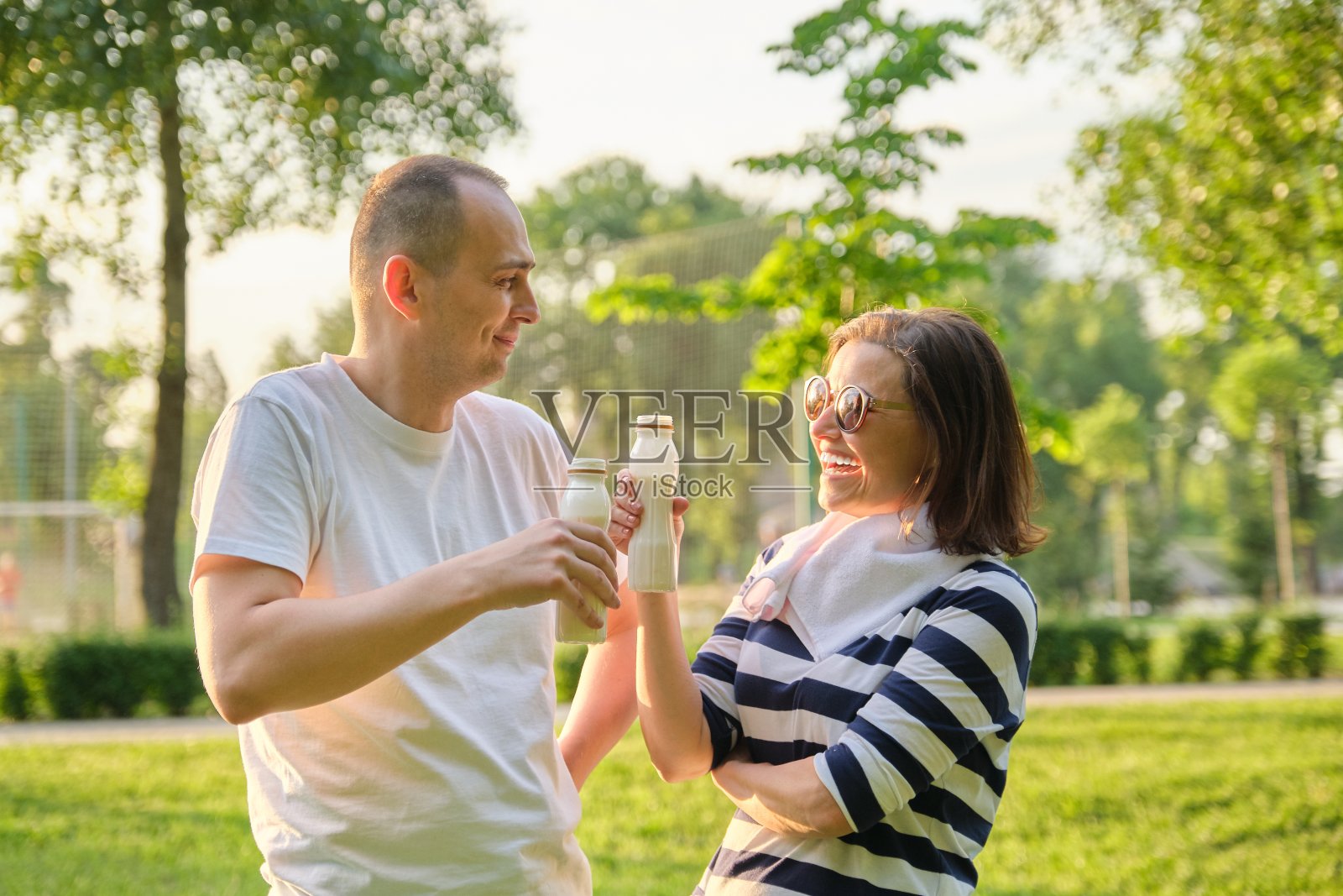 快乐成熟的情侣在公园里，休息时喝酸奶，锻炼后喝乳制品照片摄影图片
