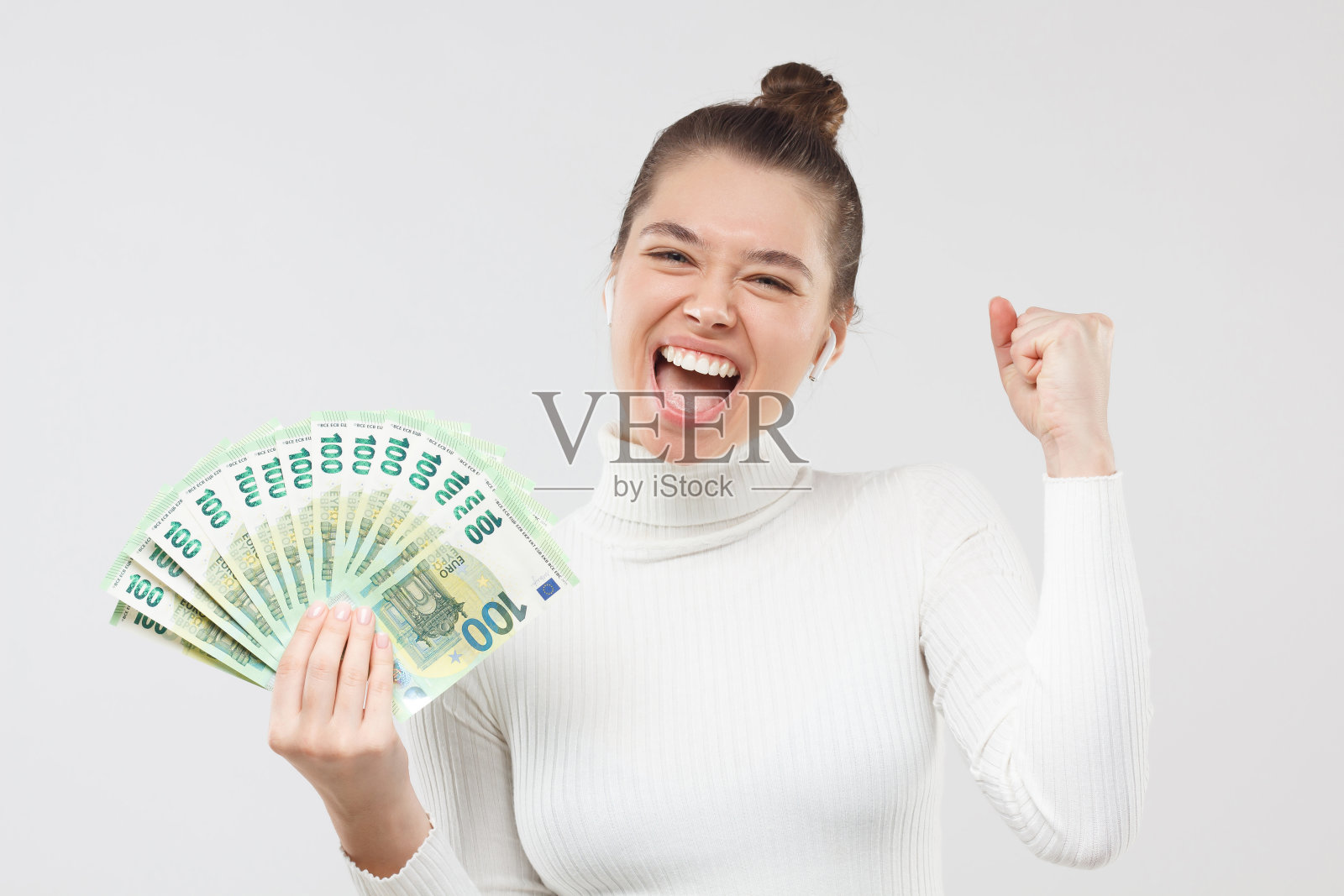 兴奋快乐的年轻女子手里拿着大量的钞票，迷着几百欧元现钞，大声叫喊着。彩票赢家的概念。照片摄影图片