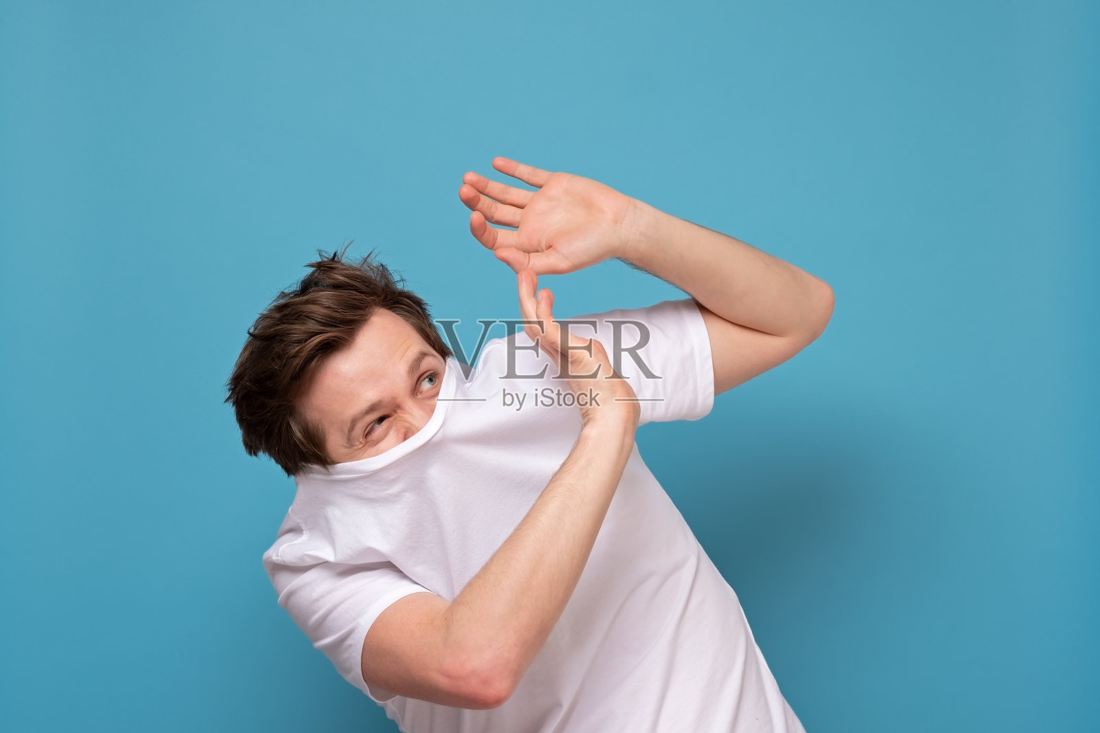 一名男子因害怕冠状病毒而躲在白衬衫后面。照片摄影图片