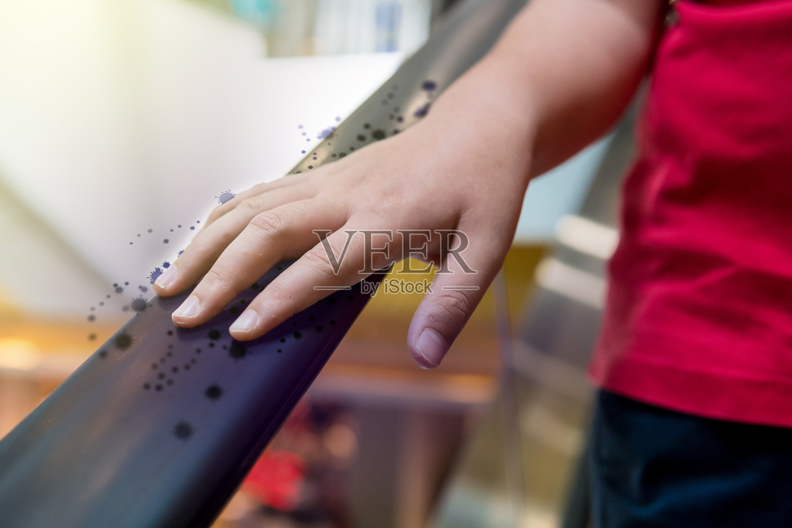 一个带着病毒或细菌的男孩在商场的自动扶梯上。照片摄影图片