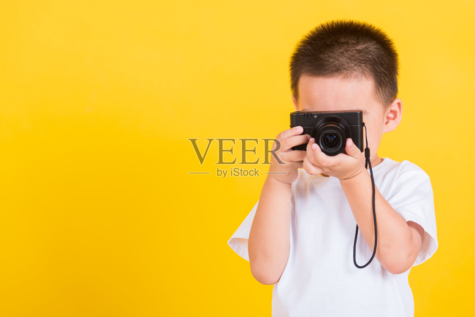 亚洲泰国快乐的肖像可爱的小快乐的孩子男孩拿着相机凑合做拍照，工作室拍摄孤立的黄色照片摄影图片