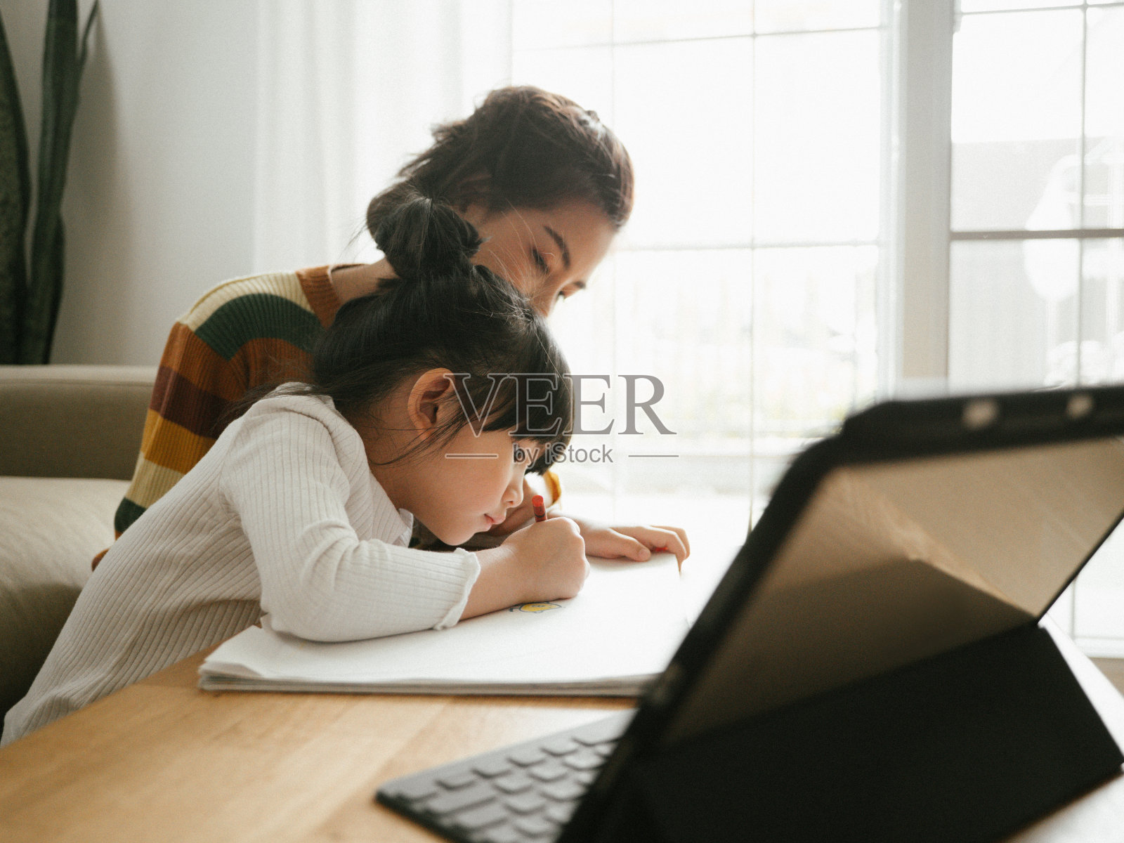 亚裔女儿在家和母亲一起参加网络课程。照片摄影图片