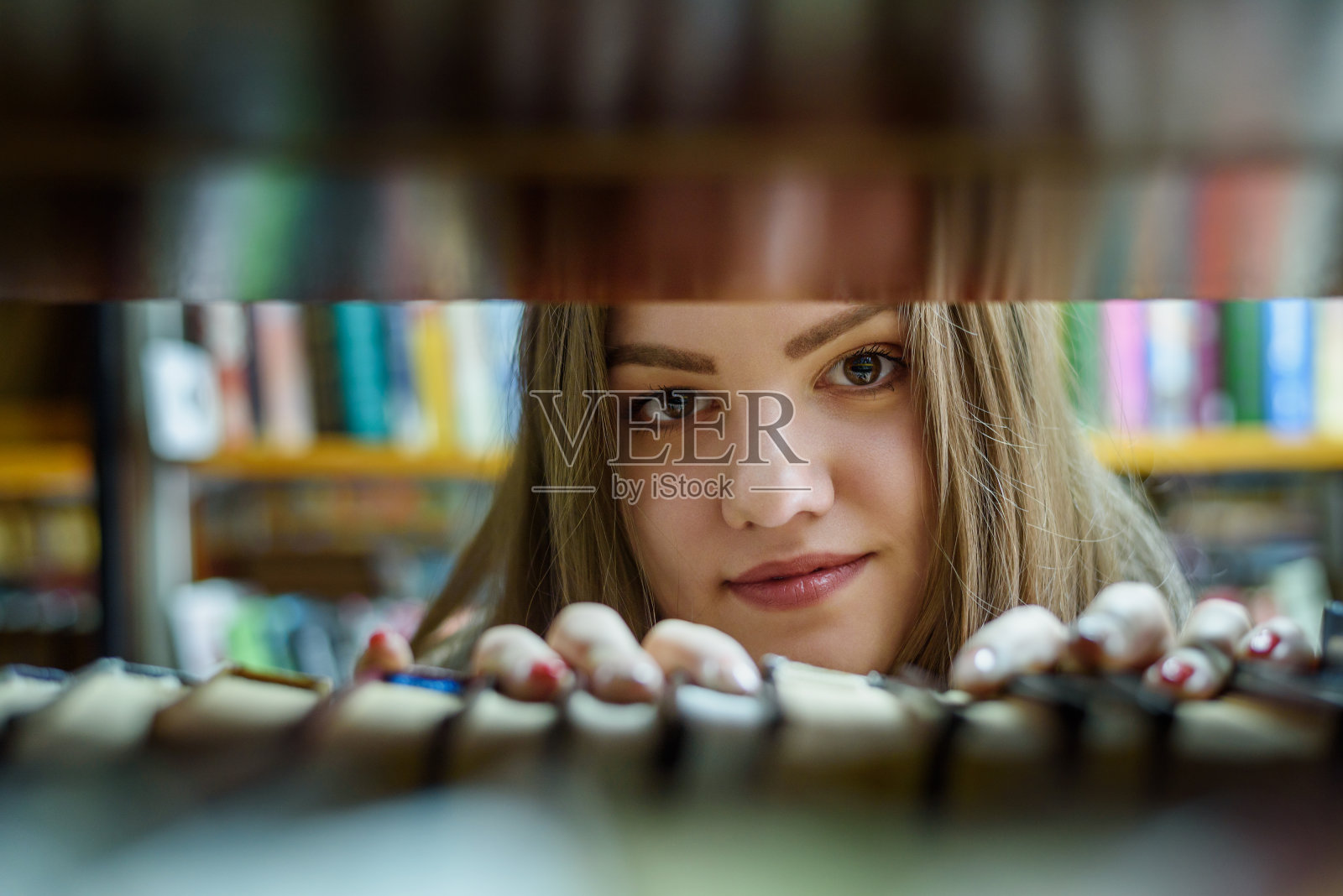 小女孩在图书馆的书架上找书照片摄影图片