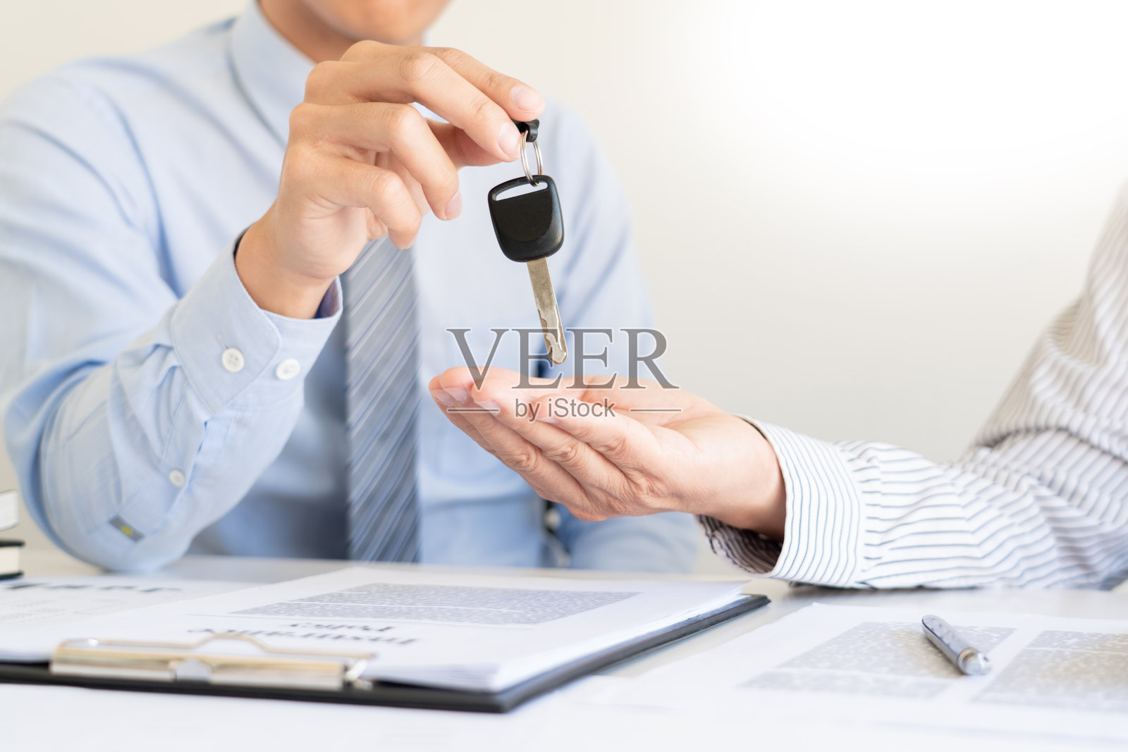 商人代理人提供夹在便签纸和银笔上的保险表格。汽车保险证书和保险单与汽车钥匙，顾问签署汽车合同。照片摄影图片