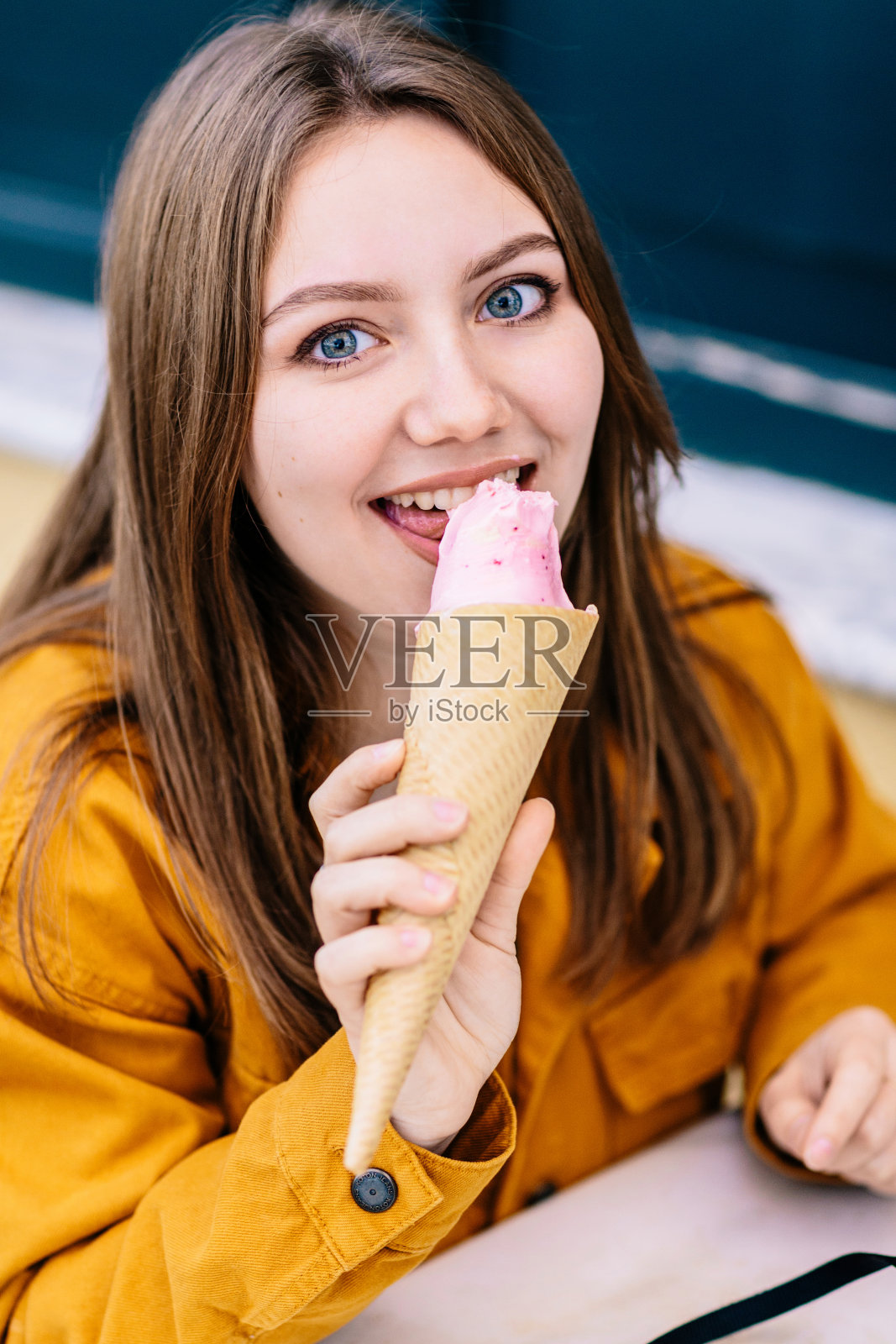 年轻的蓝眼睛女孩在吃香草冰淇淋照片摄影图片