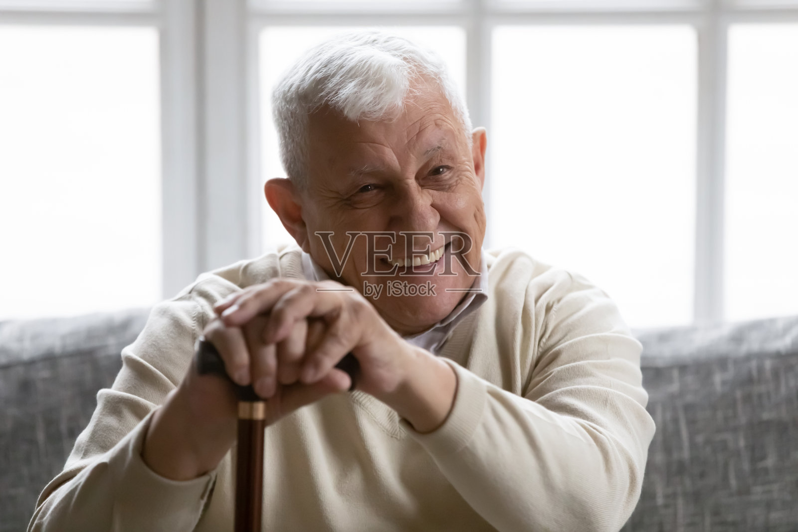 正抱着拐杖的老爷爷倚在沙发上照片摄影图片