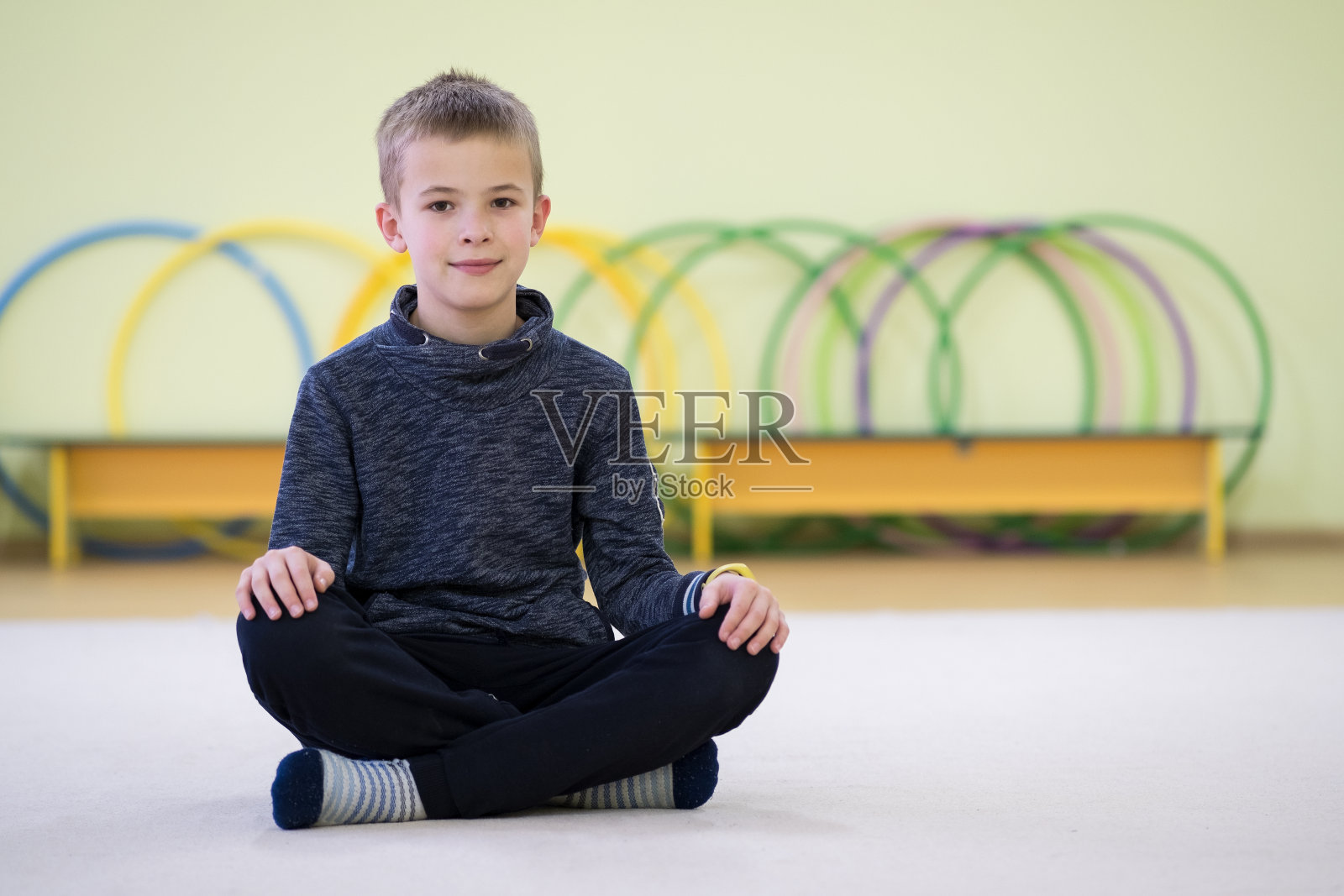在一所学校的运动室内，小男孩在训练后坐在地板上休息。照片摄影图片