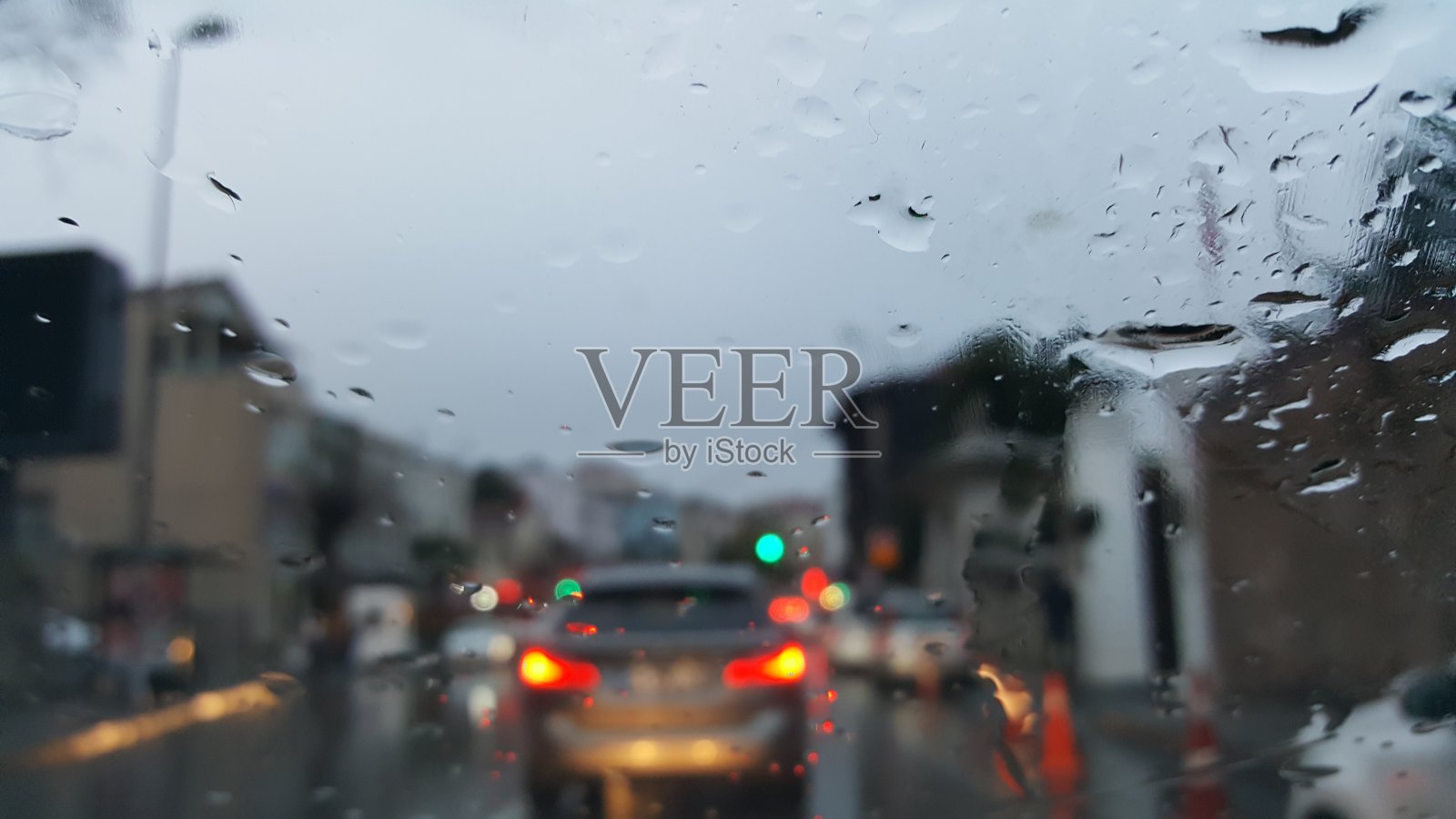 雨点打在汽车的玻璃在交通，城市的场景在雨中照片摄影图片