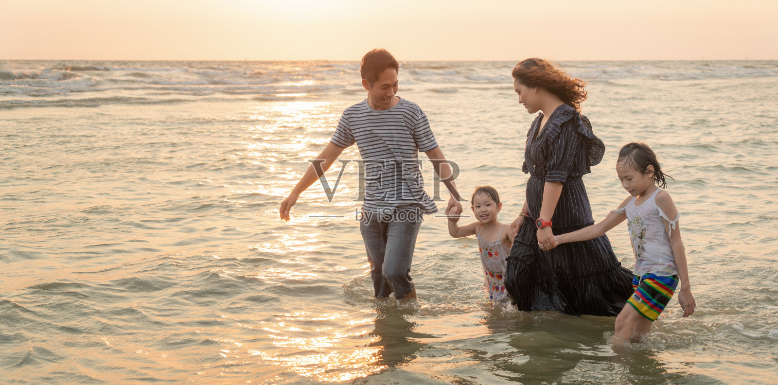 海滩上快乐的亚洲家庭。幸福的家庭的概念照片摄影图片