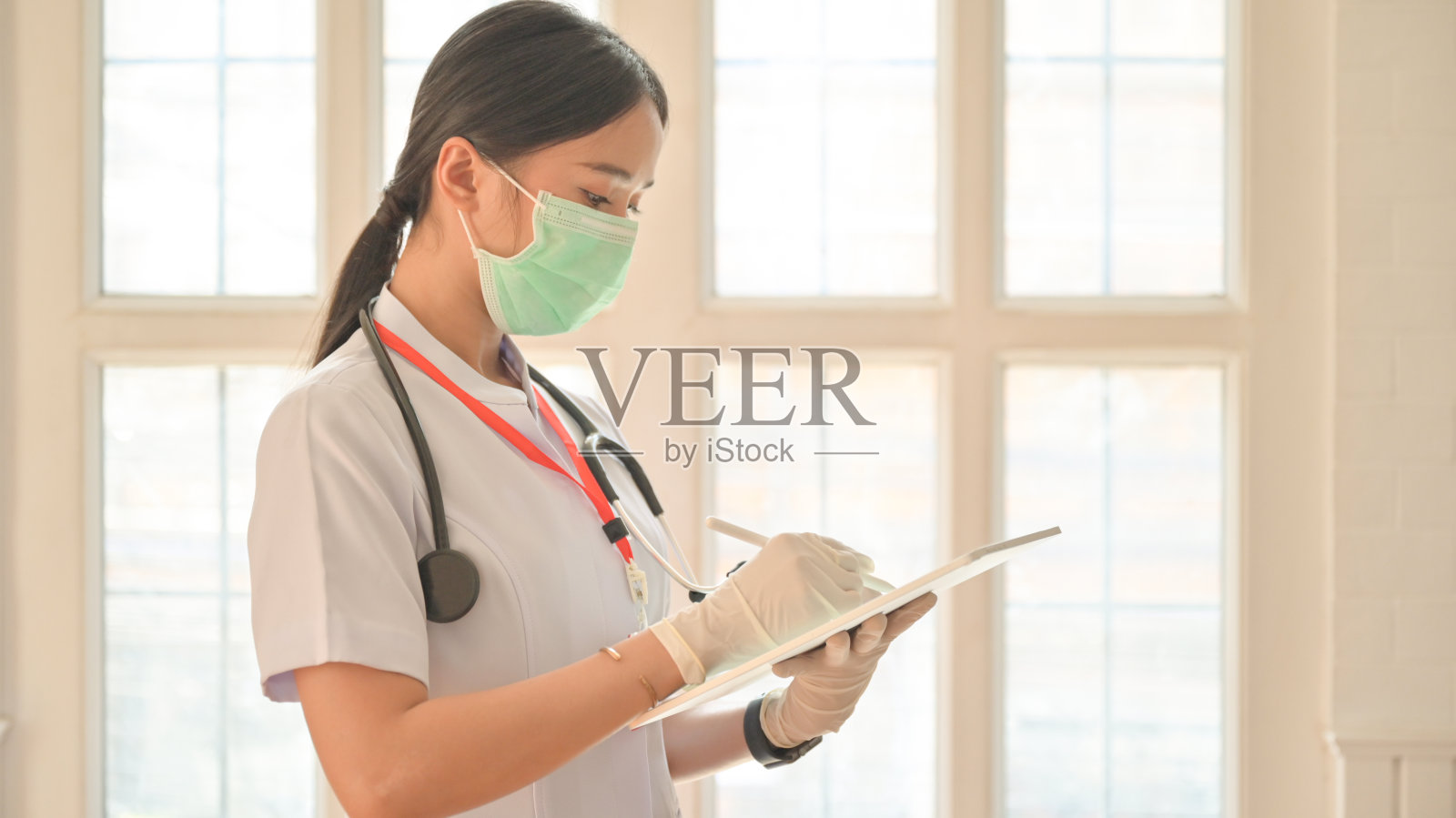 护士戴着手套用平板记录covid-19病毒感染者的剪影。照片摄影图片