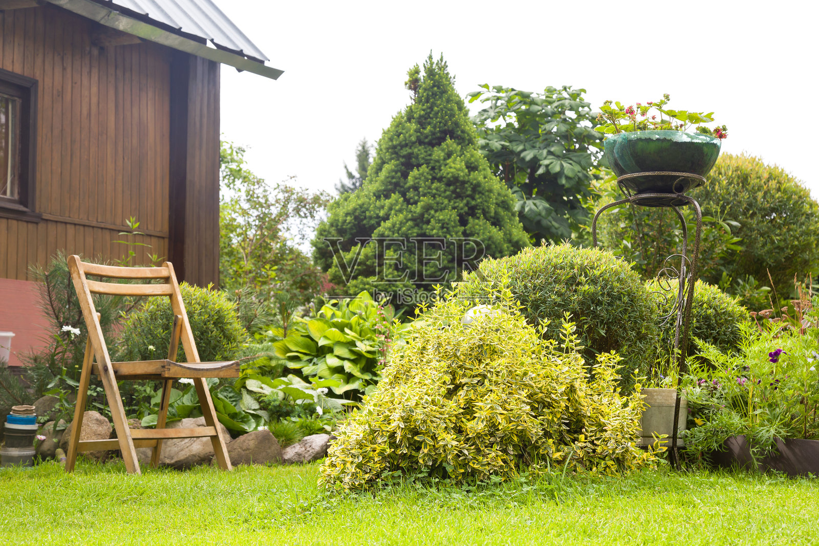 美丽的花园，盛开的花坛和一个木制的花园椅子照片摄影图片