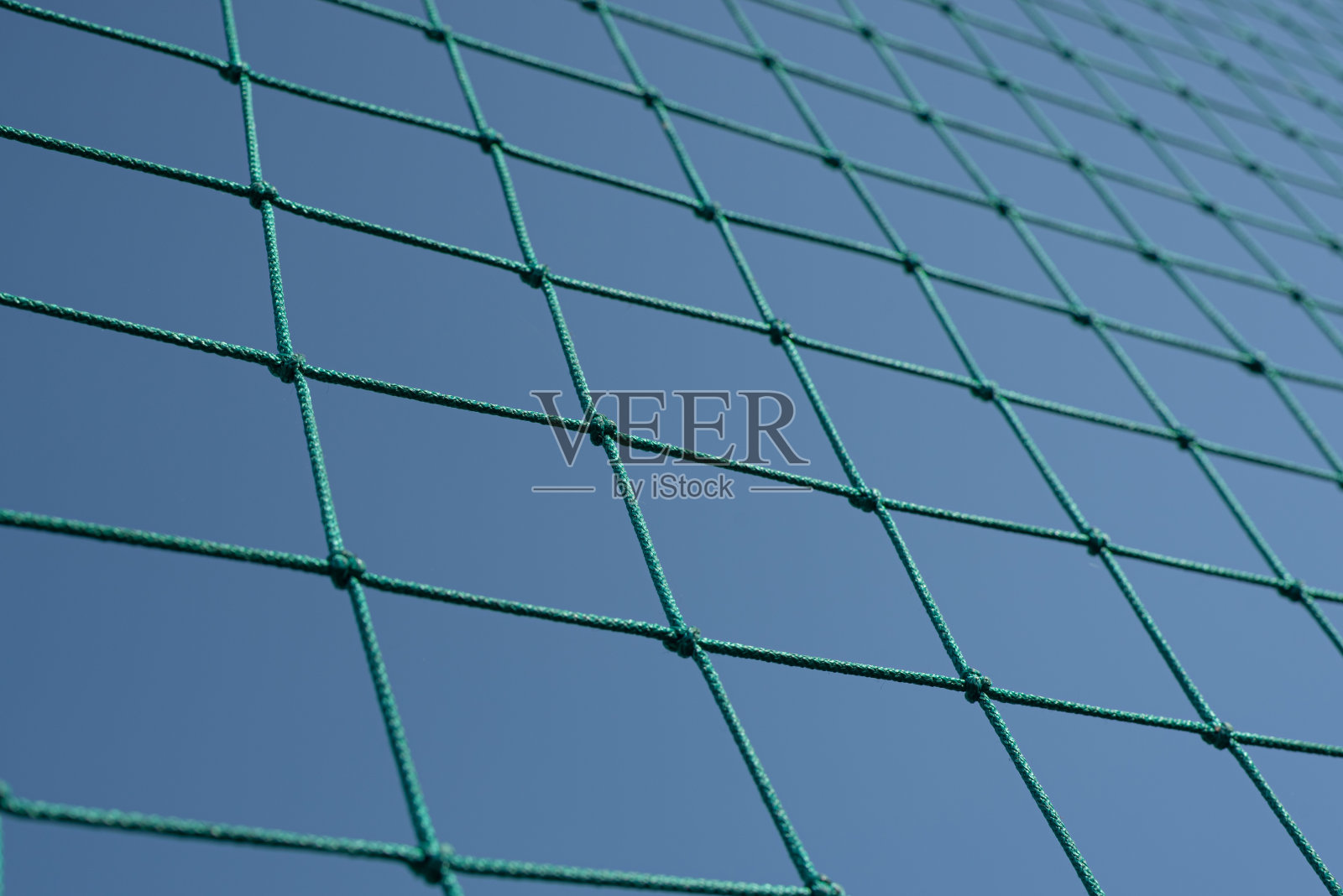 绿色网球或排球网对抗蓝天。网格图案抽象背景。照片摄影图片
