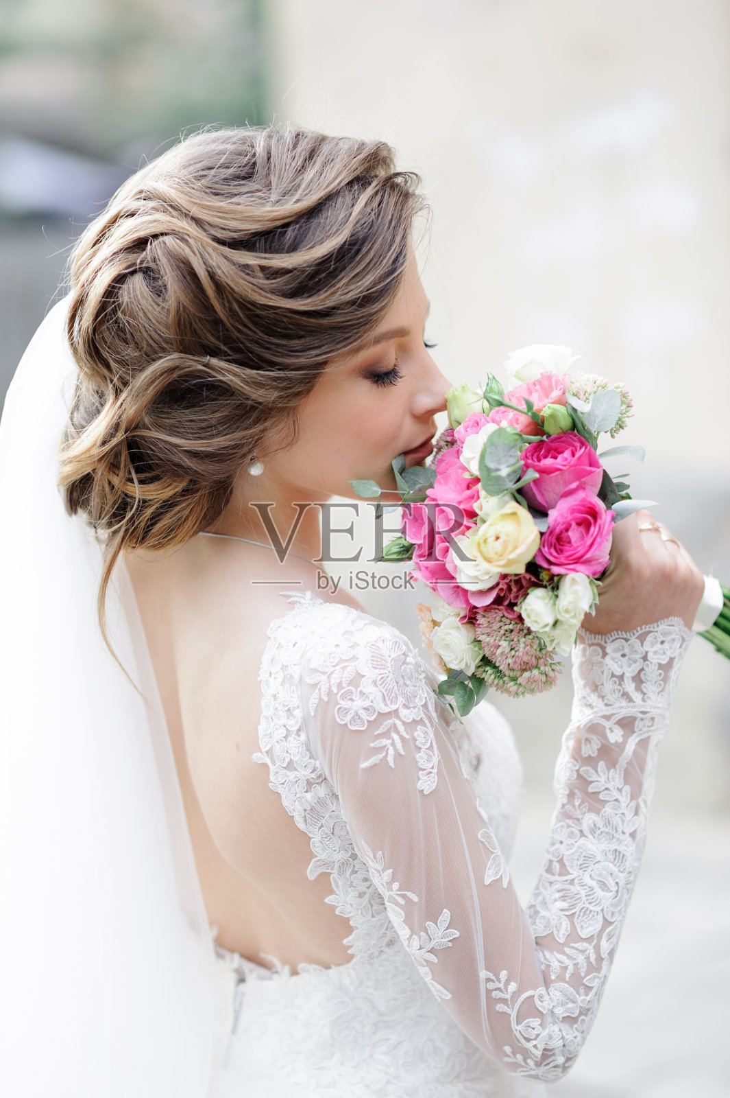 一个年轻美丽的新娘在老城的肖像。拿着婚礼花束的女孩的手。照片摄影图片