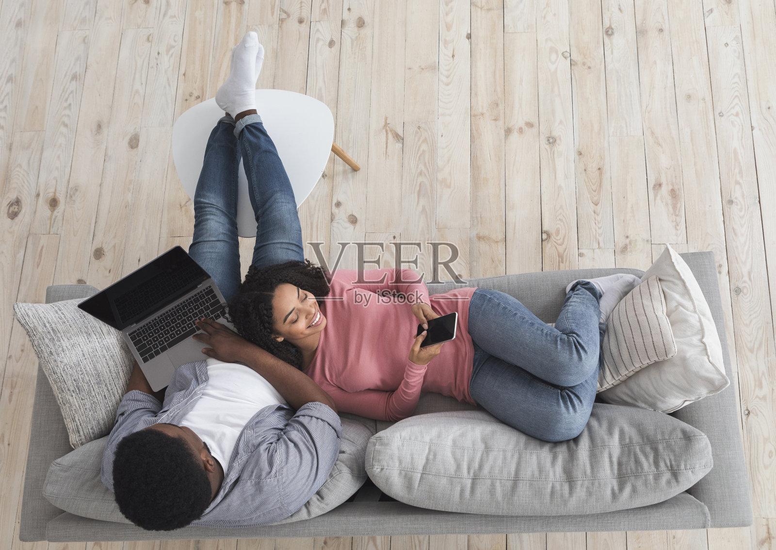 年轻的非洲裔美国夫妇在家里用笔记本电脑和智能手机放松照片摄影图片