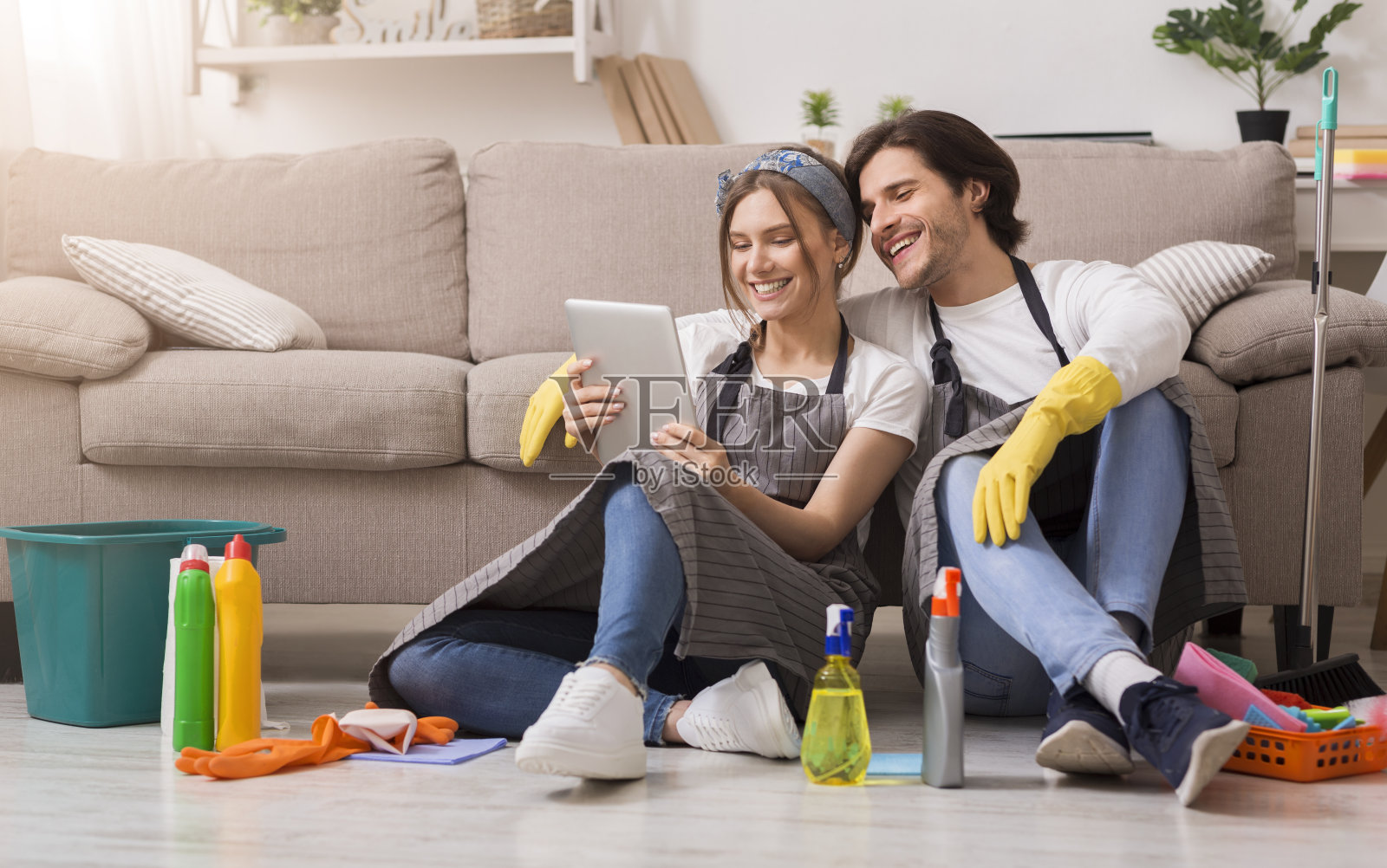 一对微笑的夫妇在打扫完公寓后在地板上用平板电脑放松照片摄影图片
