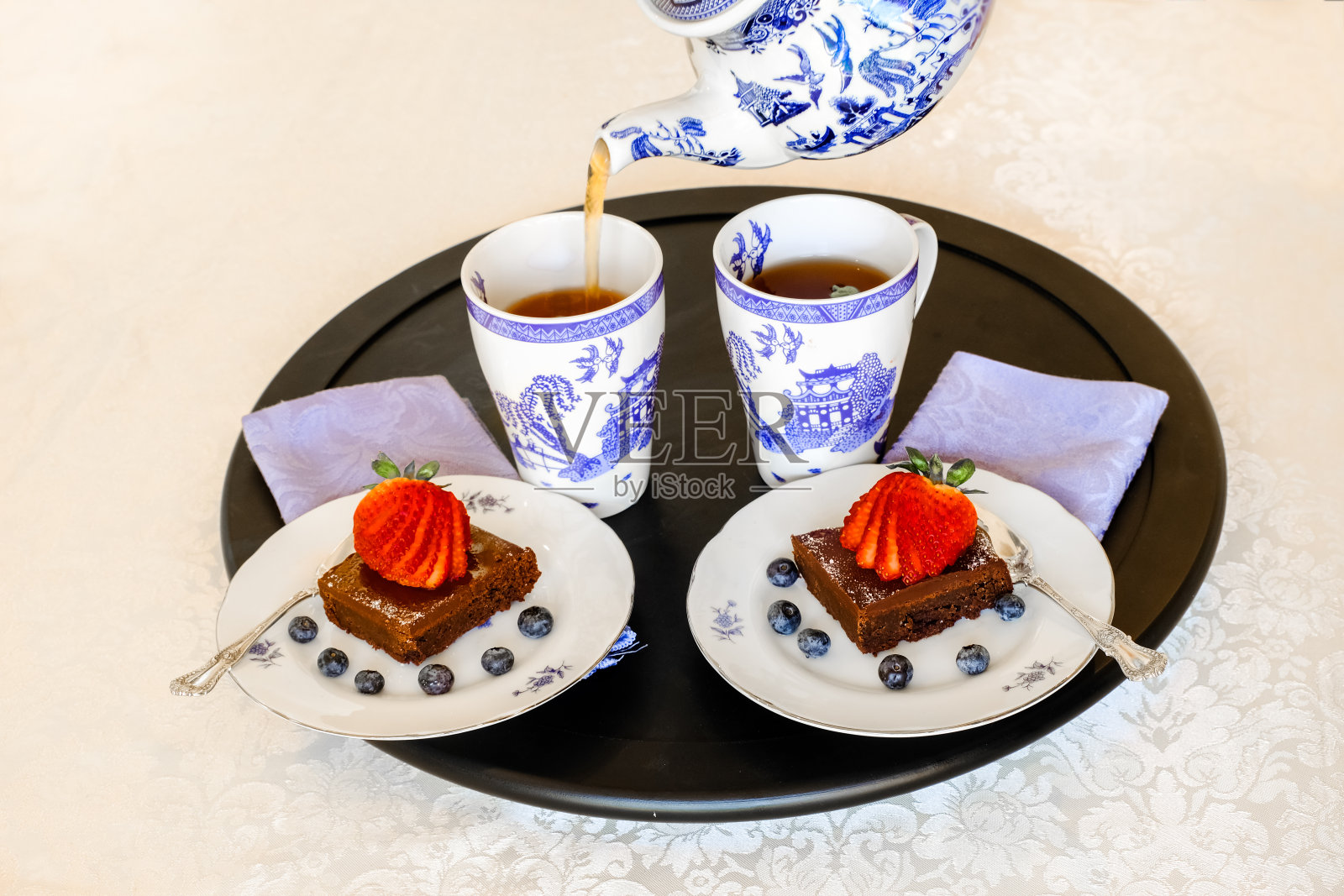圆形托盘，两个盘子，两个杯子和一个茶壶照片摄影图片
