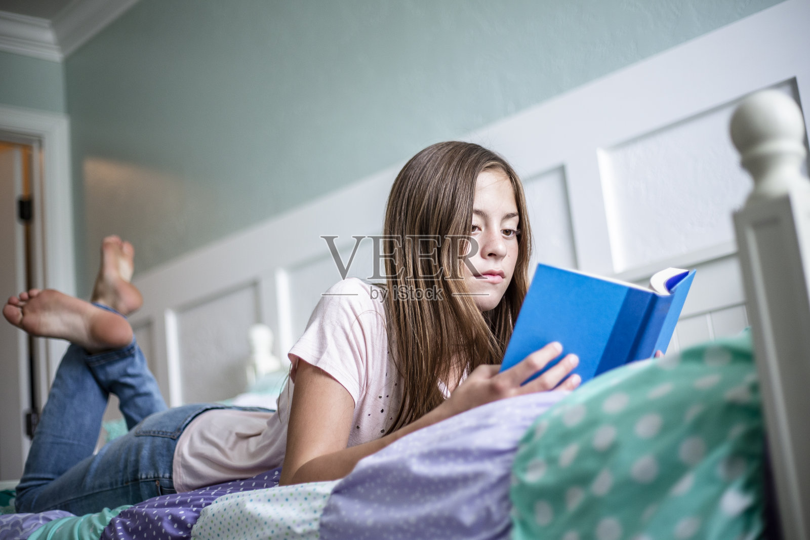 一个十几岁的女孩躺在卧室的床上看书。生活和学习照片照片摄影图片