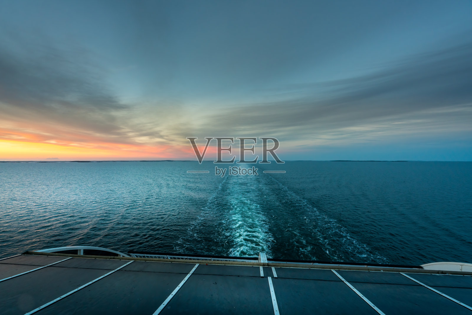 美丽的日落海景与船的尾迹从游轮的船尾看到的地平线。照片摄影图片