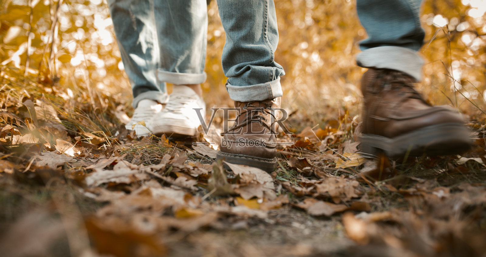一对穿着牛仔裤的情侣在秋叶上散步照片摄影图片