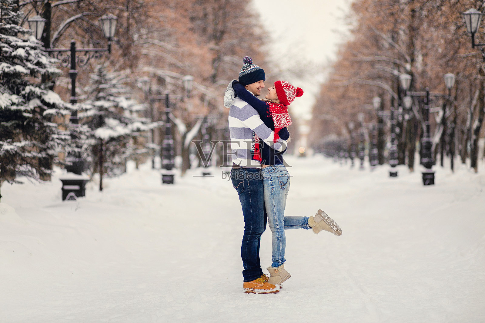 一对年轻情侣在冬天的公园里拥抱亲吻照片摄影图片
