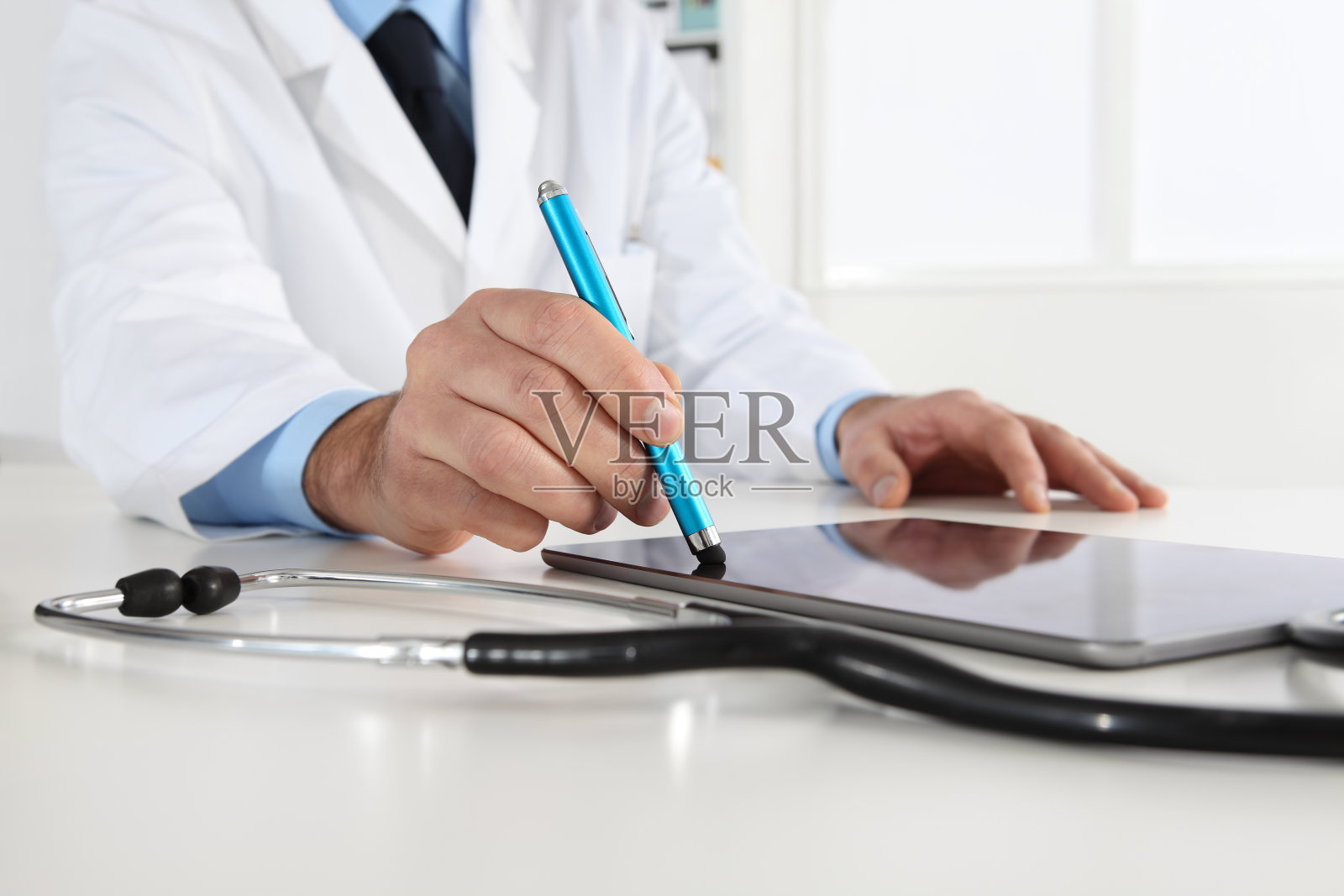 医生手触屏数字平板书写处方在医务室办公桌近距离照片摄影图片