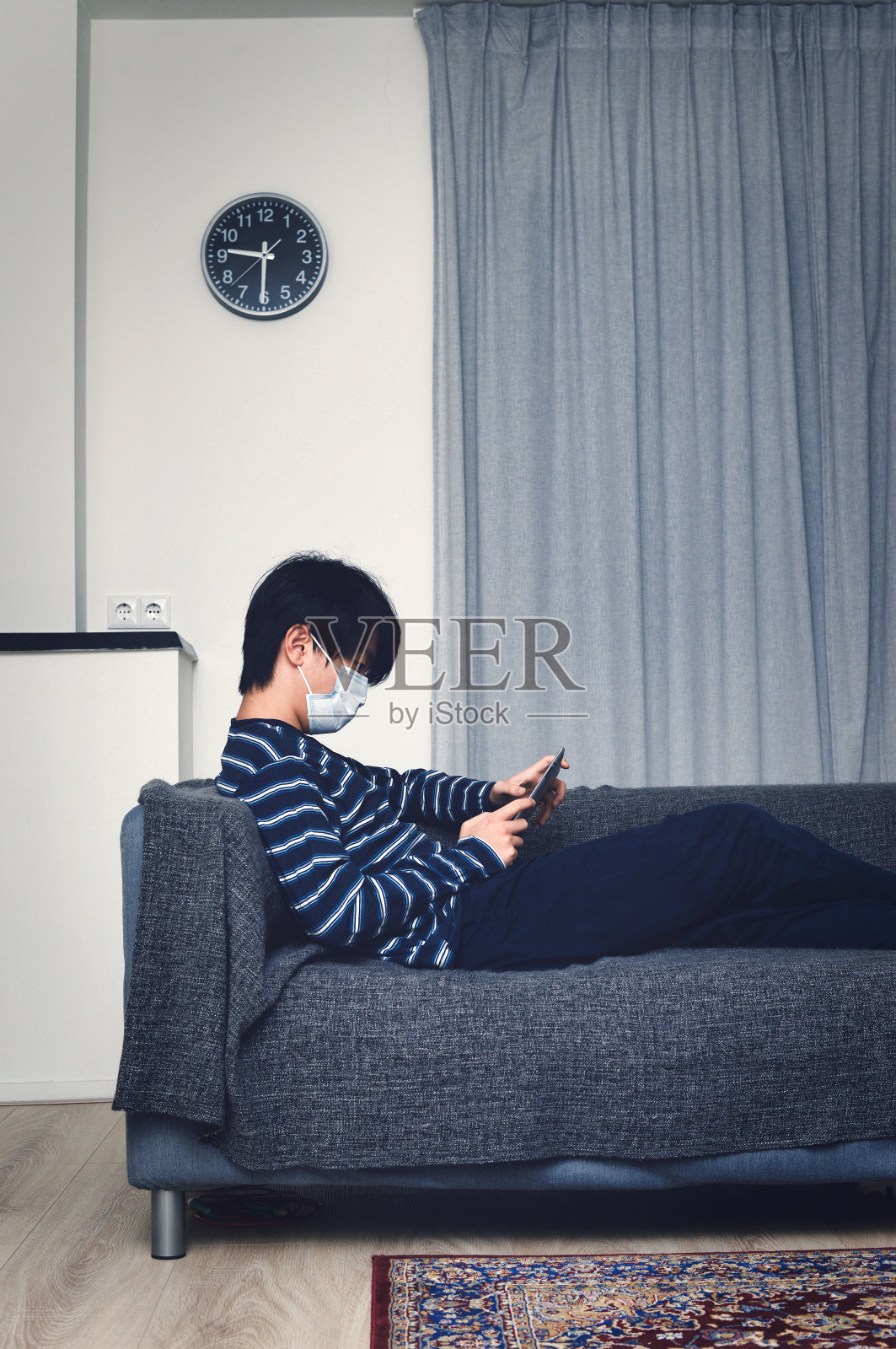 年轻的亚洲孩子在家，戴着口罩，在平板电脑上玩游戏照片摄影图片