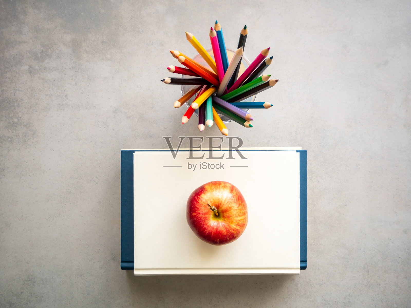 俯视图彩色铅笔和一个红苹果上的一堆书，灰色的背景照片摄影图片