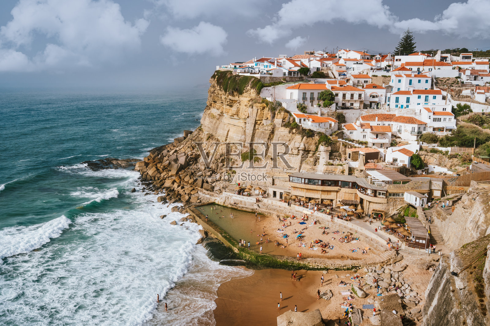 在美丽的Azenhas do Mar村庄和波浪保护海滩的假日氛围。悬崖边上的白色白垩房屋。明亮的天空和白云。辛特拉地标，葡萄牙，欧洲照片摄影图片