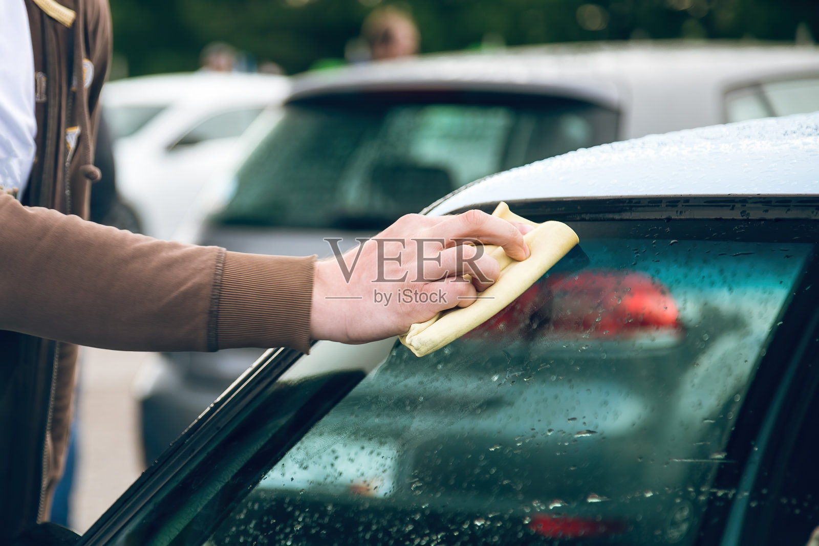 一个男人用餐巾擦汽车挡风玻璃。特写镜头。照片摄影图片
