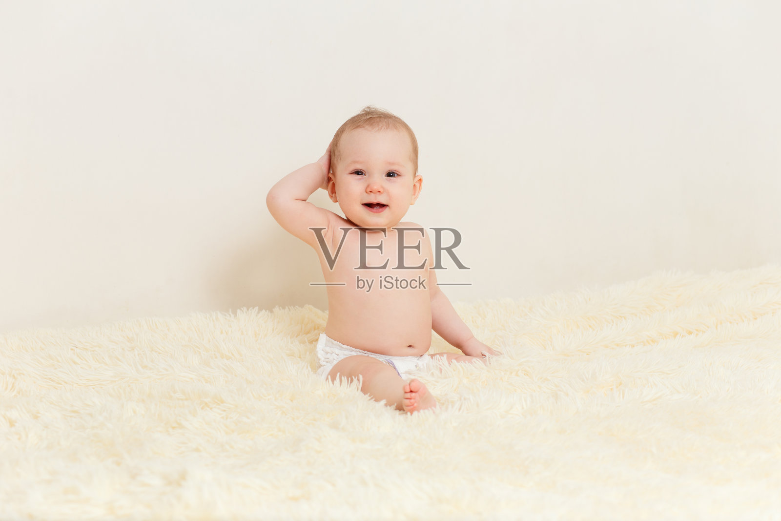 可爱的女婴舒服地坐在毛茸茸的毯子上照片摄影图片