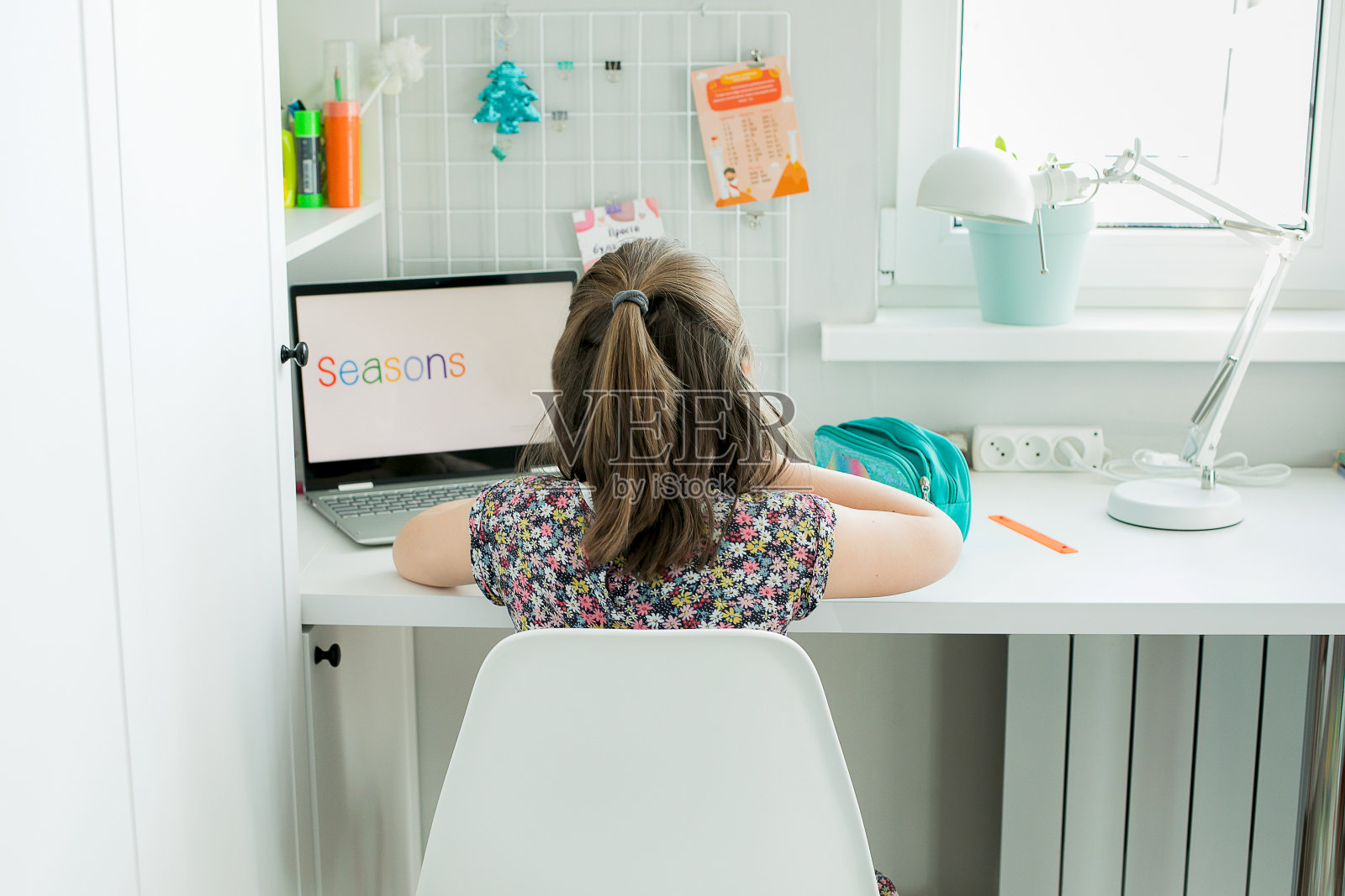 7-8岁的女学生在学习，使用笔记本电脑。家庭学校、在线教育、家庭教育、隔离、冠状病毒概念。生活方式，家居室内概念。照片摄影图片
