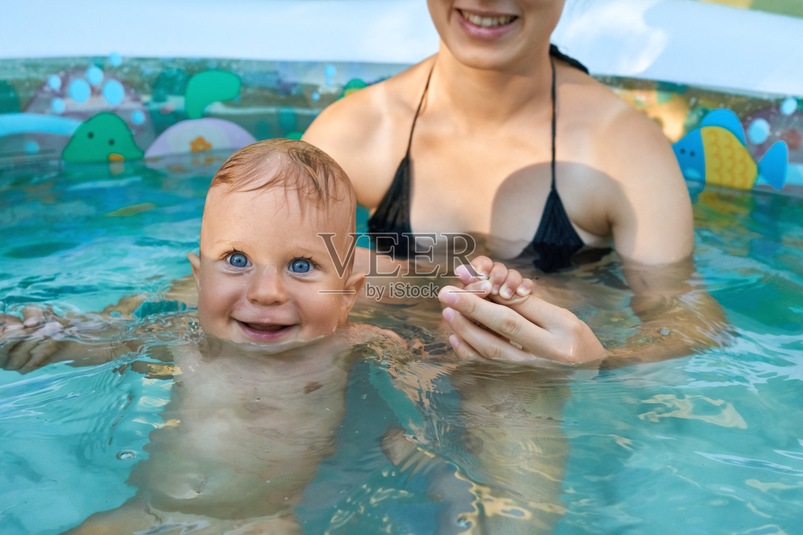充气泳池里有个年轻女人和她的小儿子照片摄影图片