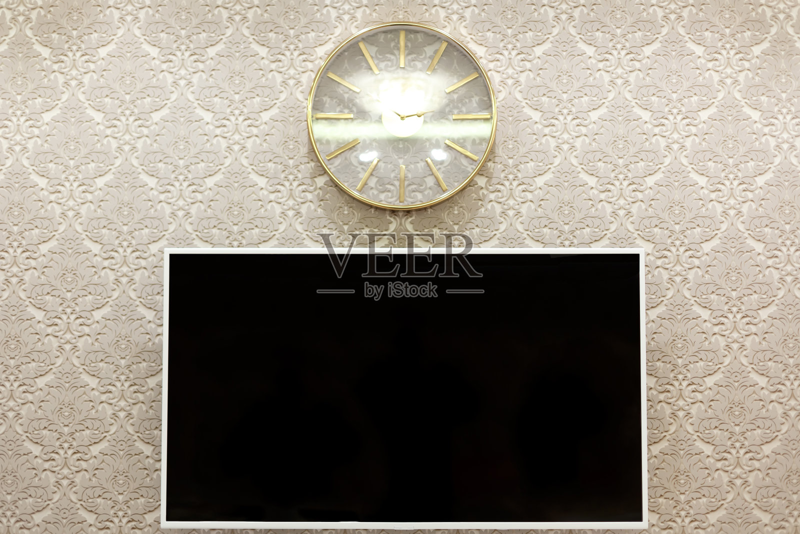 墙上挂着一台白色相框的电视机。墙上挂着一个圆形机械钟。照片摄影图片