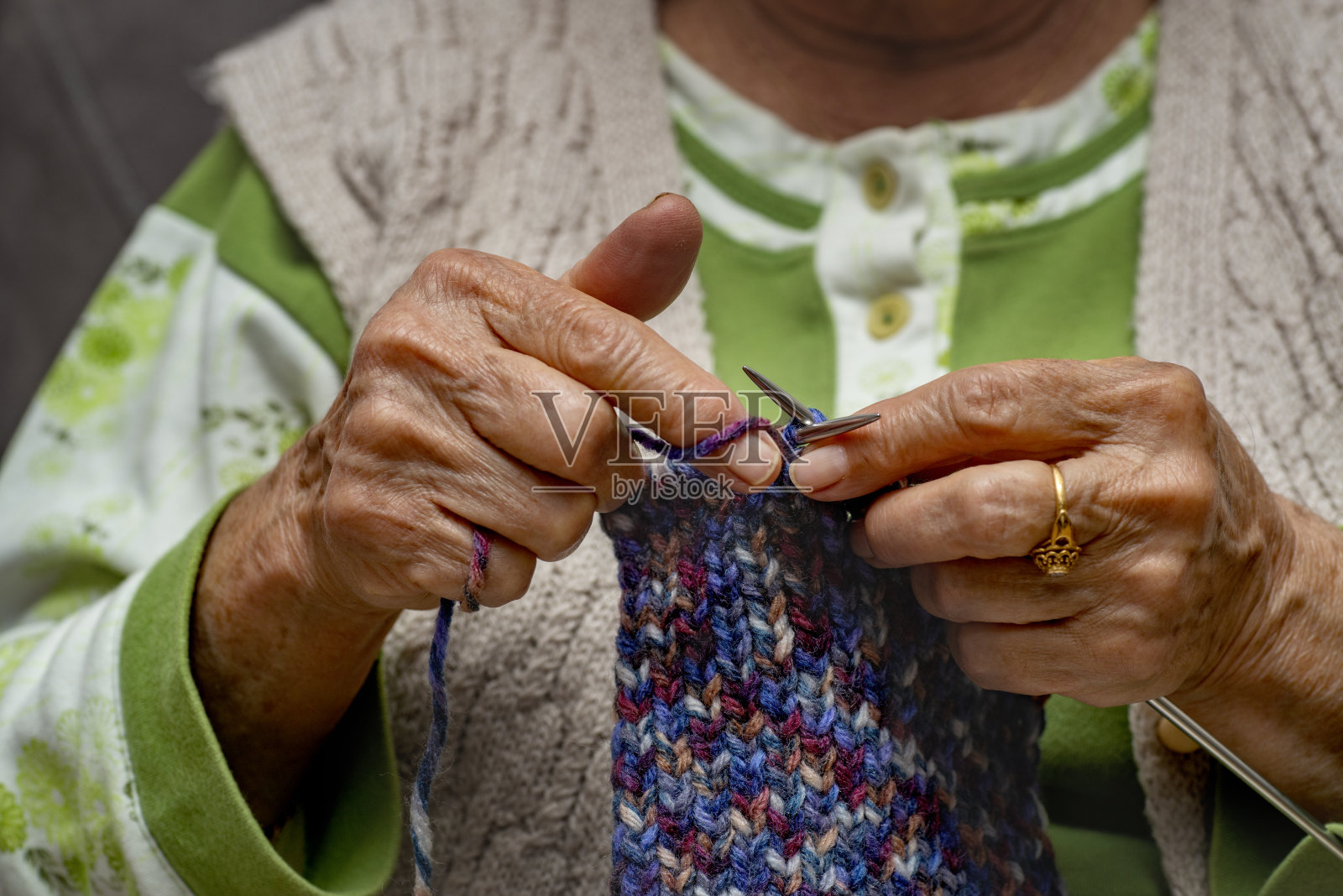 老妇人正在家里用彩绳编织。照片摄影图片