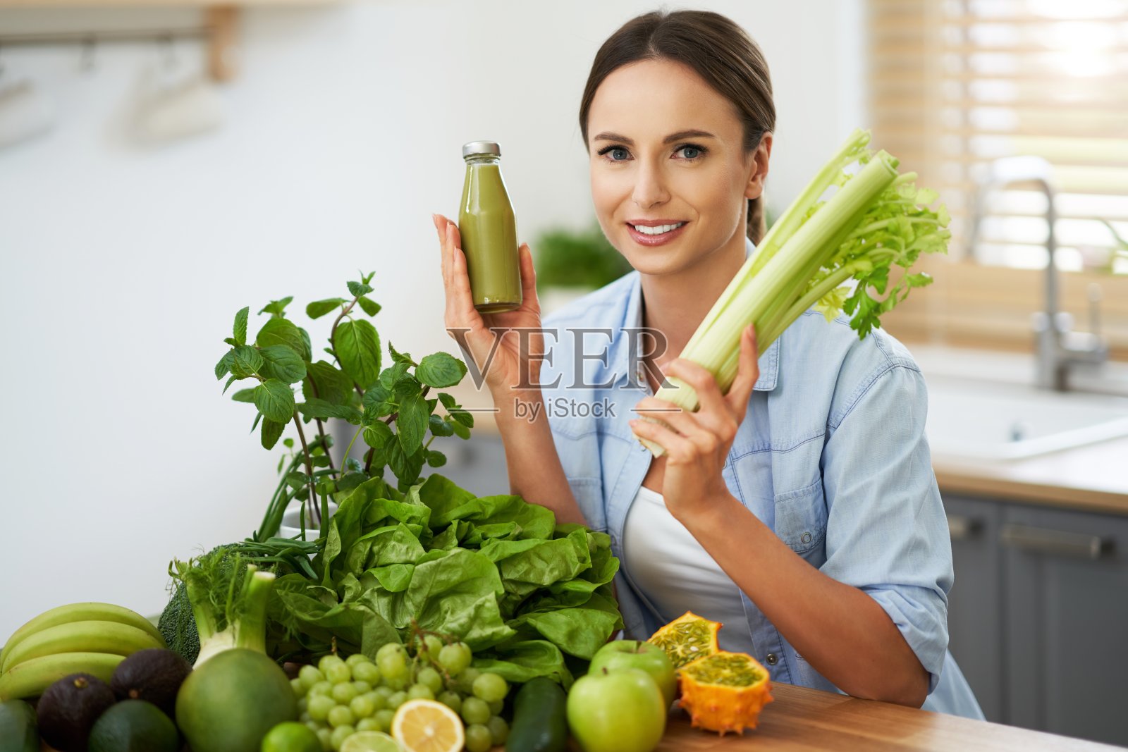 健康的成年女性，厨房里有绿色食物照片摄影图片